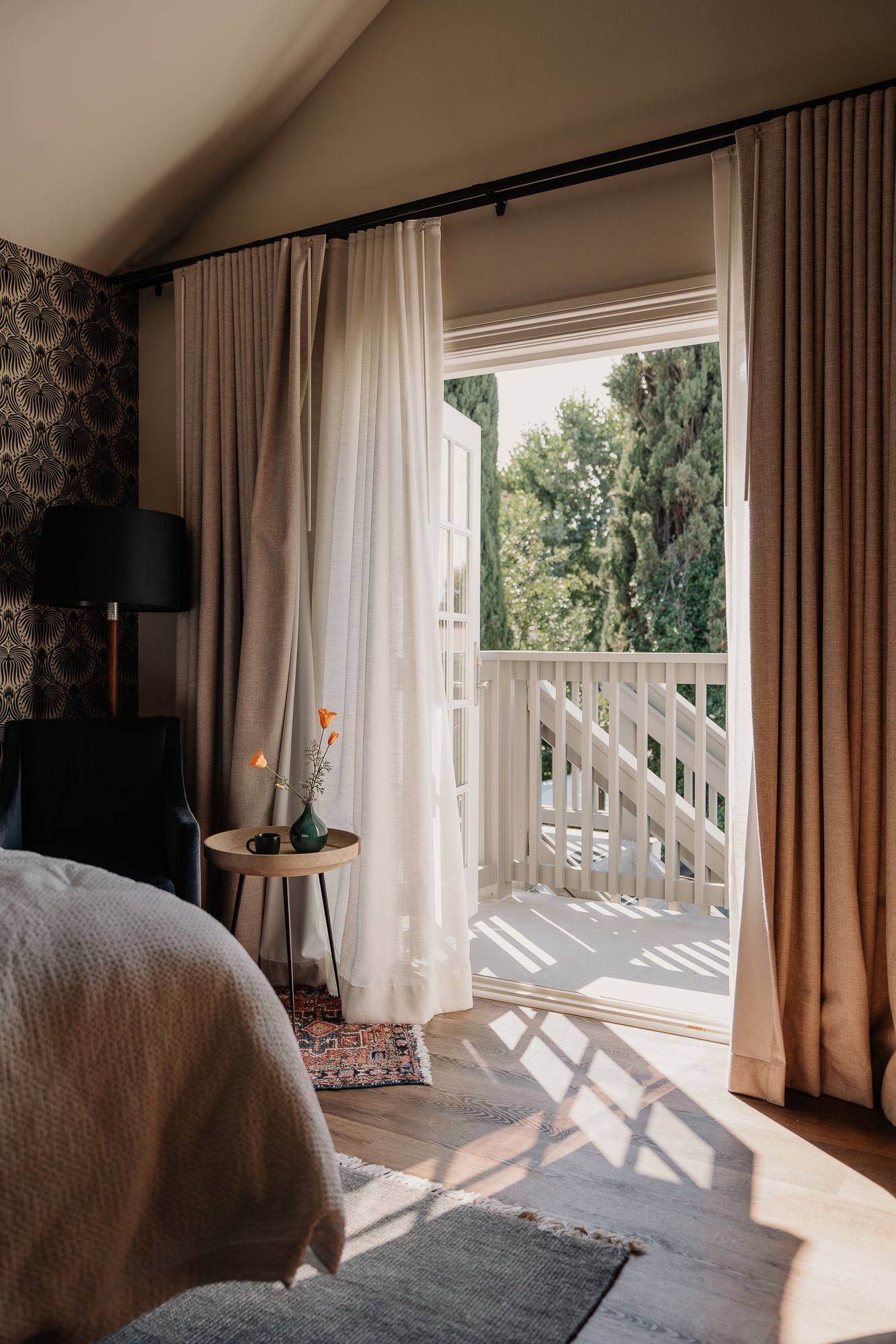 A series of bright bedroom windows with white curtains and natural sunlight casting geometric shadows on the floor.