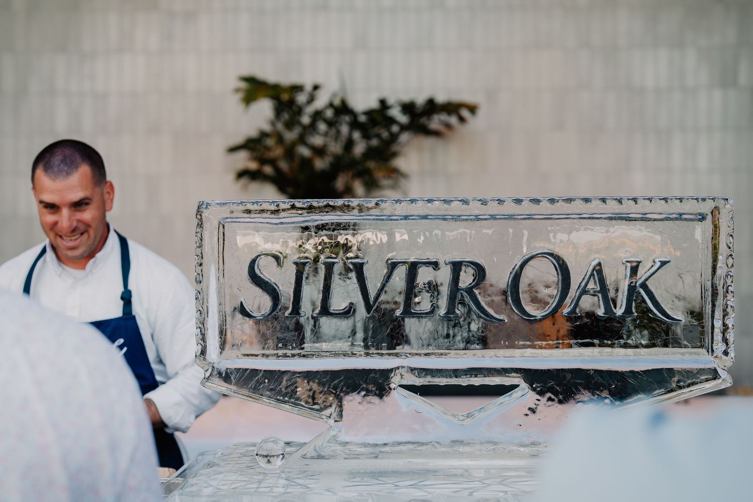 Chef stands beside a Silver Oak branded ice sculpture at an elegant winery event.