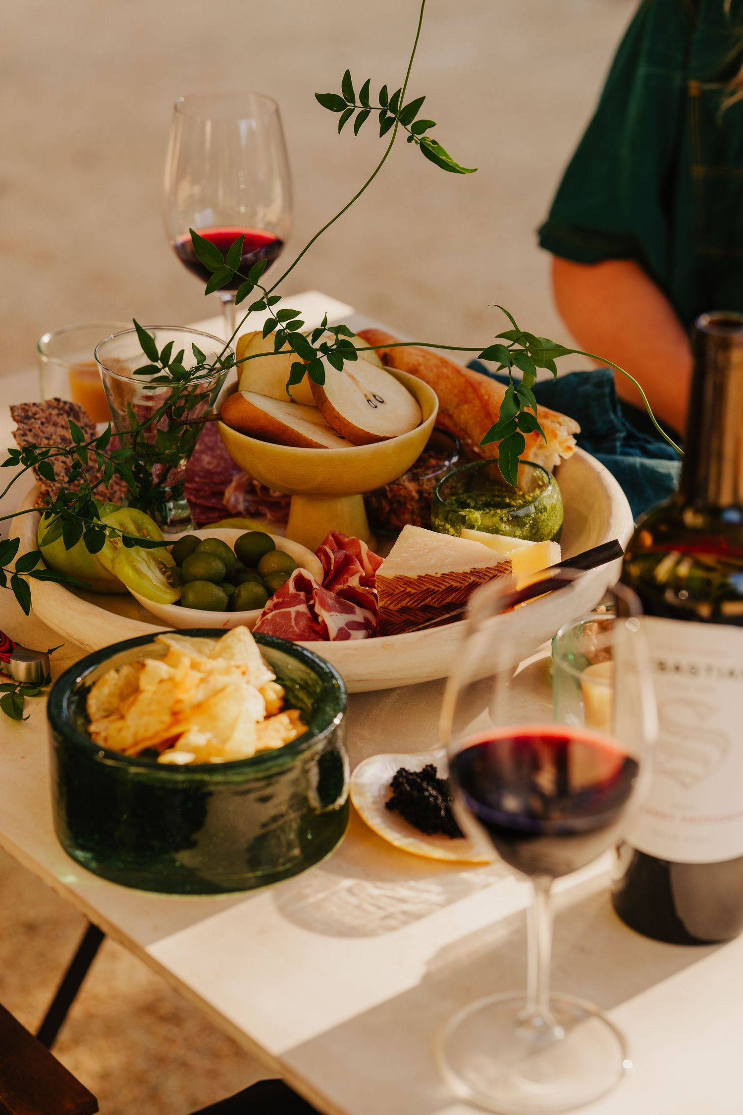 Elegant charcuterie board with cheese, meats, fruits and greens alongside glasses of Sebastiani red wine.