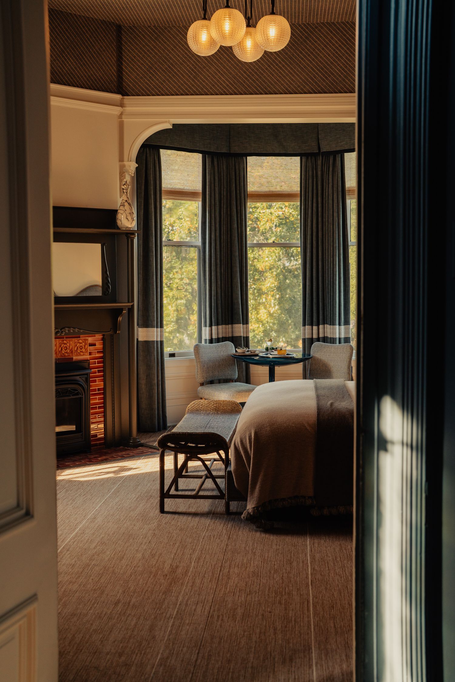 Luxurious hotel suite interior with modern furnishings, large windows, and warm lighting creating an inviting atmosphere.