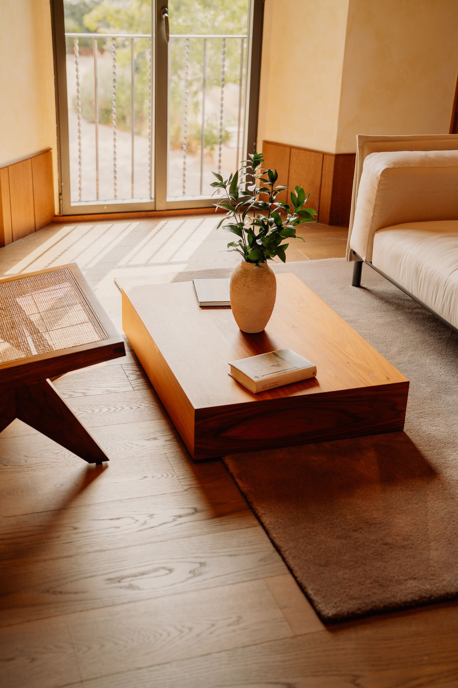 A series of minimalist wooden benches with potted plants in a sunlit room with warm wood flooring.