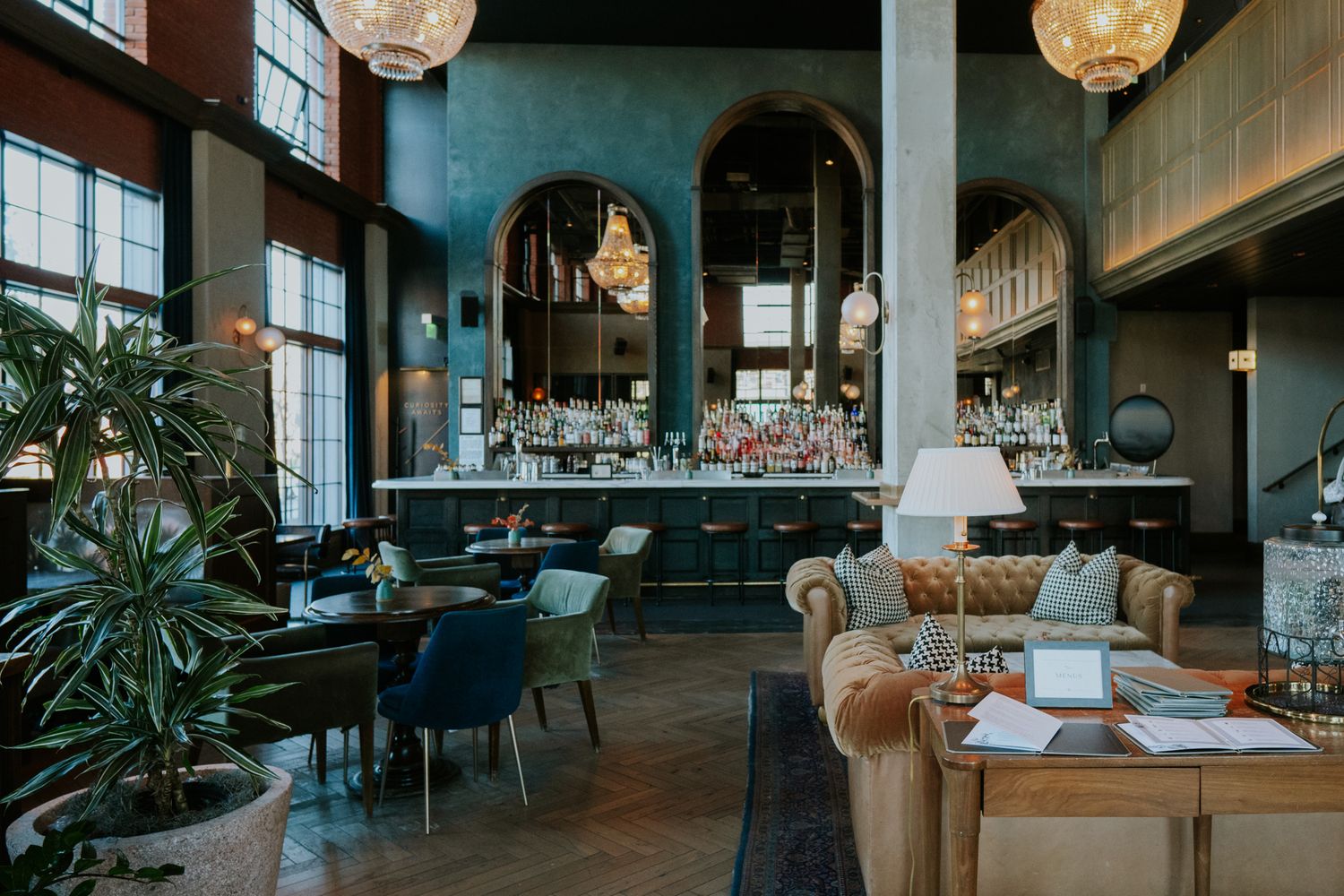 Modern restaurant interior with teal walls, hanging pendant lights, and contemporary dining furniture.
