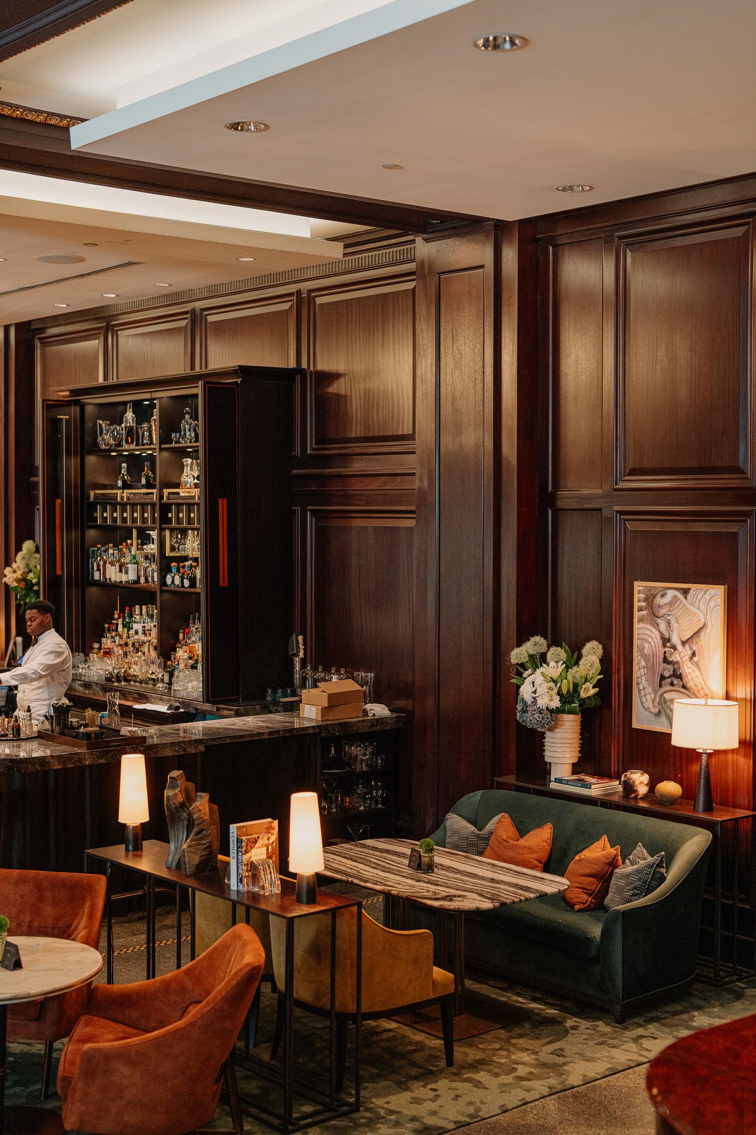 Luxurious hotel bar lounge with dark wood paneling, plush seating, and warm ambient lighting.