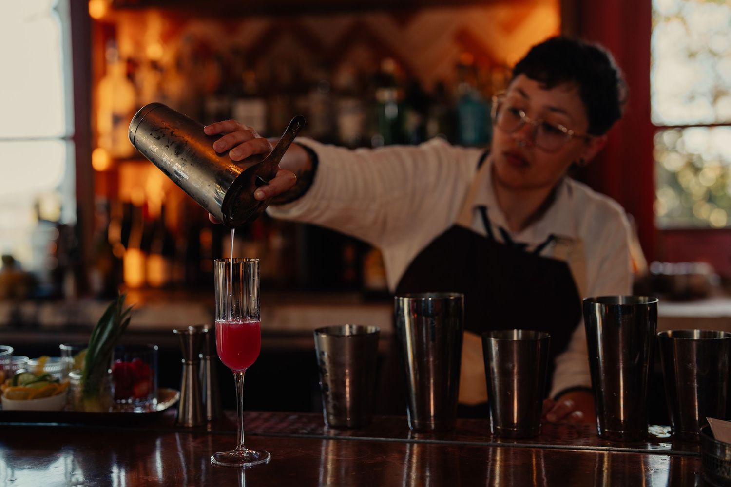 Bar scene with cocktails and glasses illuminated by warm ambient lighting.