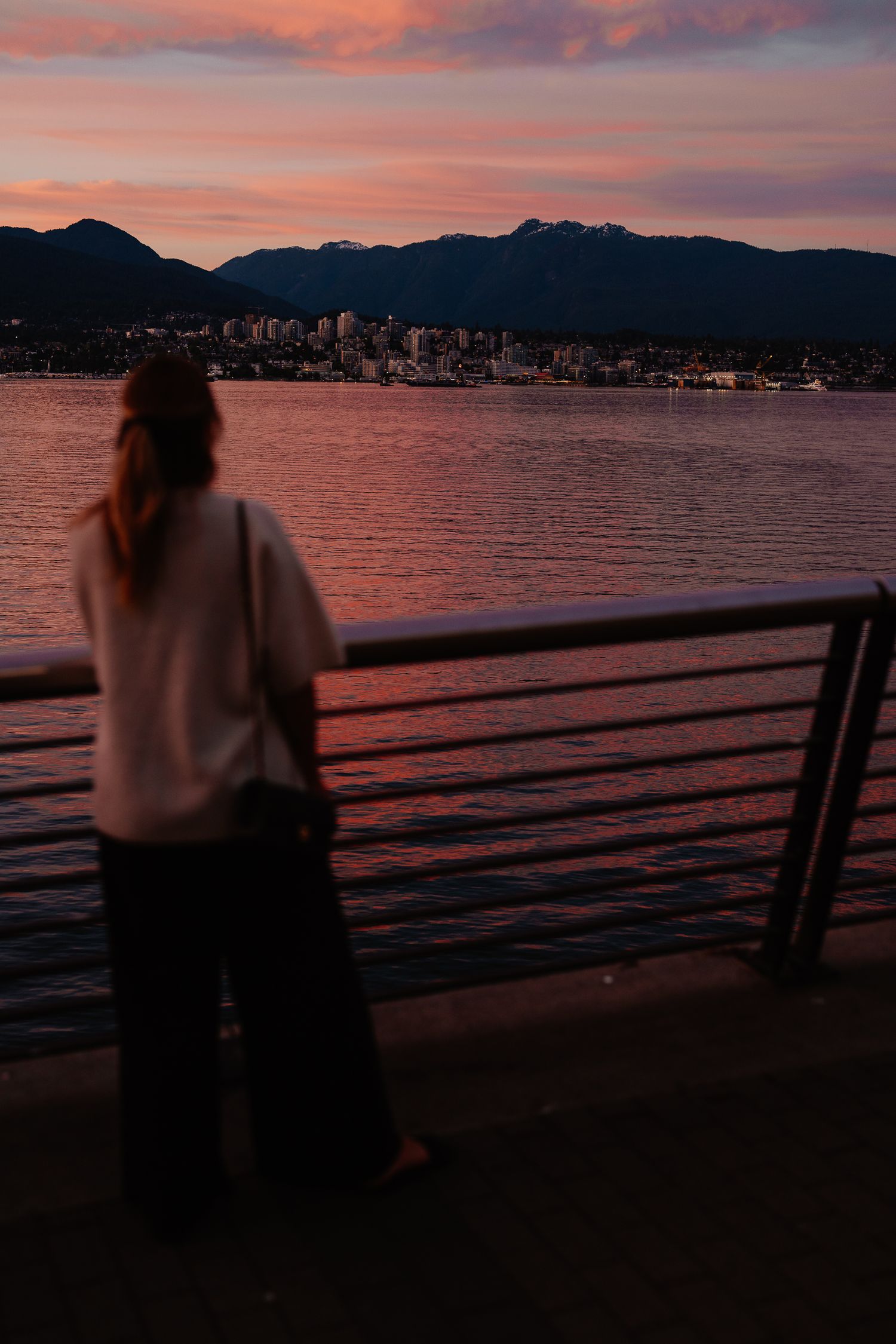 Scenic coastal sunset view with silhouetted mountains, waterfront buildings, and railing in a progressive sequence of frames.
