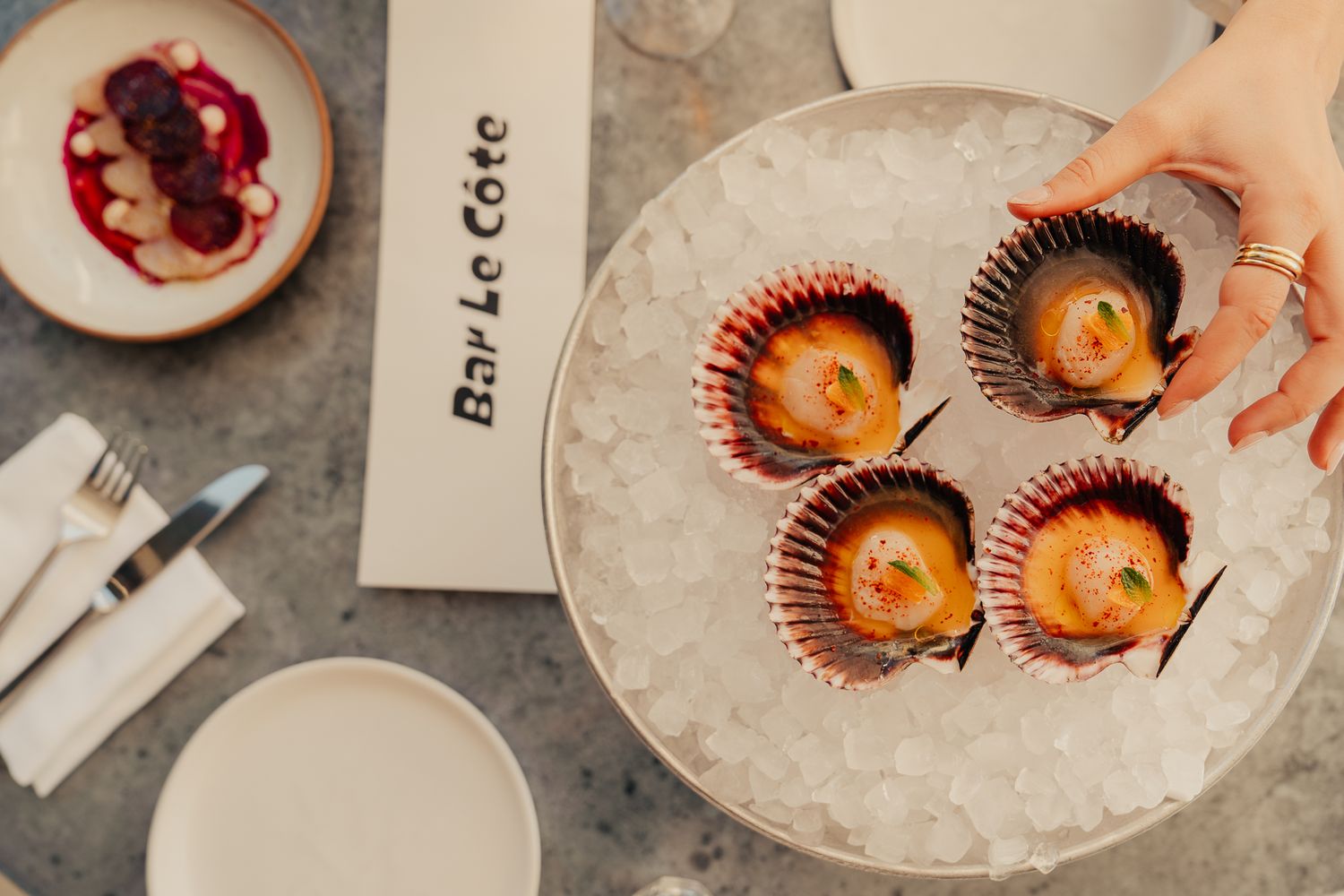 Fresh scallops served on ice in shells on a plate at Bar La Cote restaurant.
