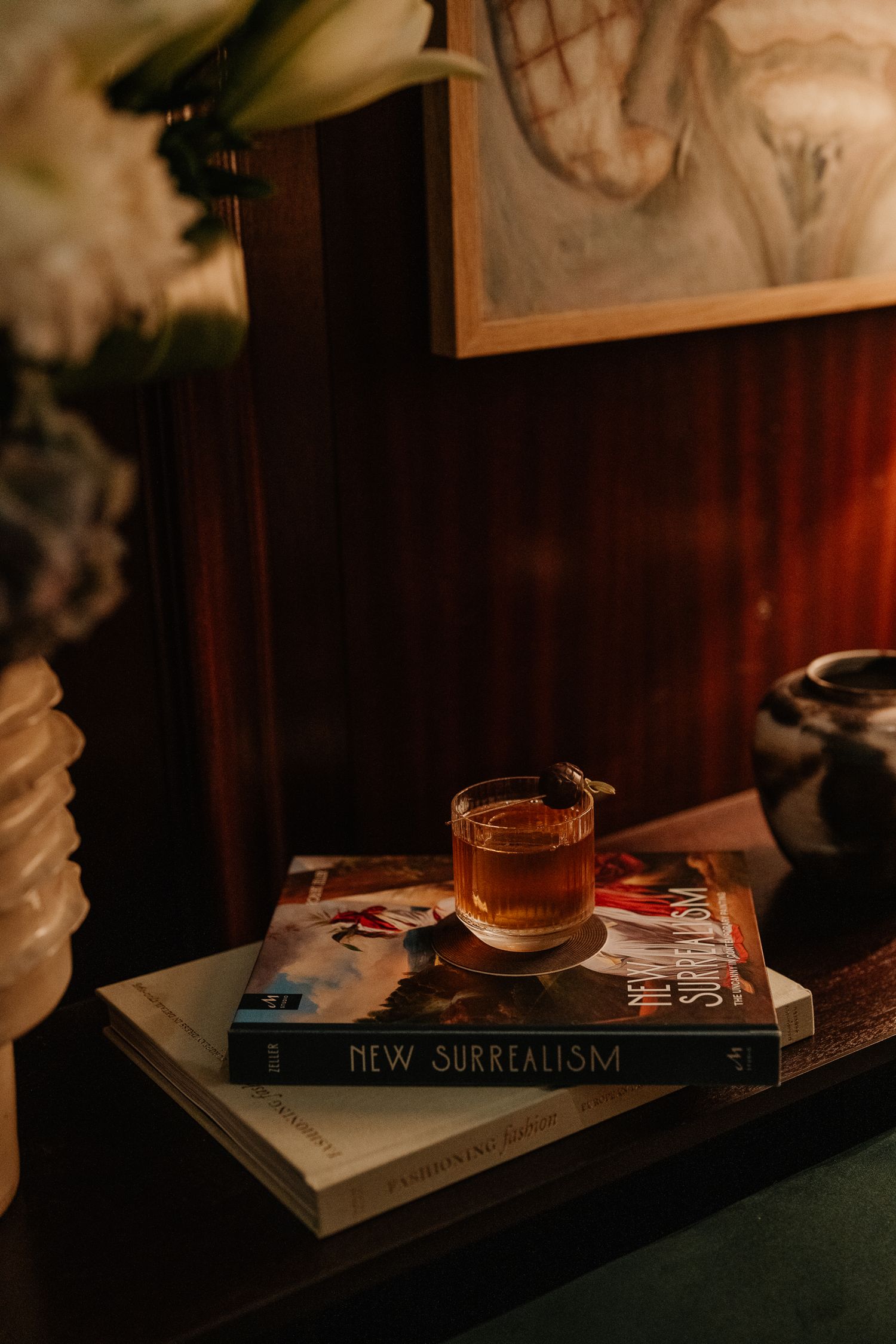 A book titled 'New Surrealism' sits on a dark surface in moody lighting creating an artistic composition.