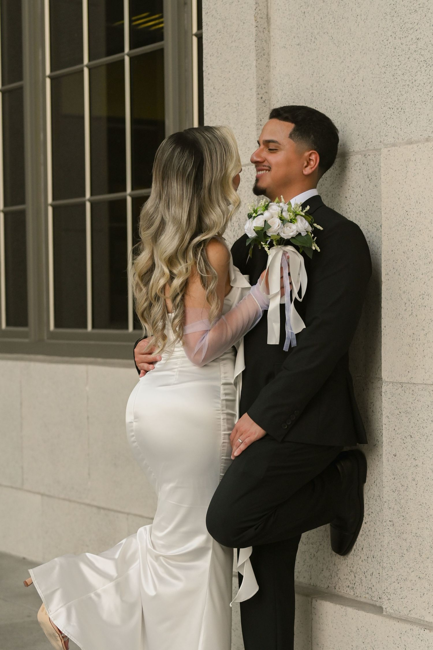 Candid courthouse wedding moment with couple against stone architecture.