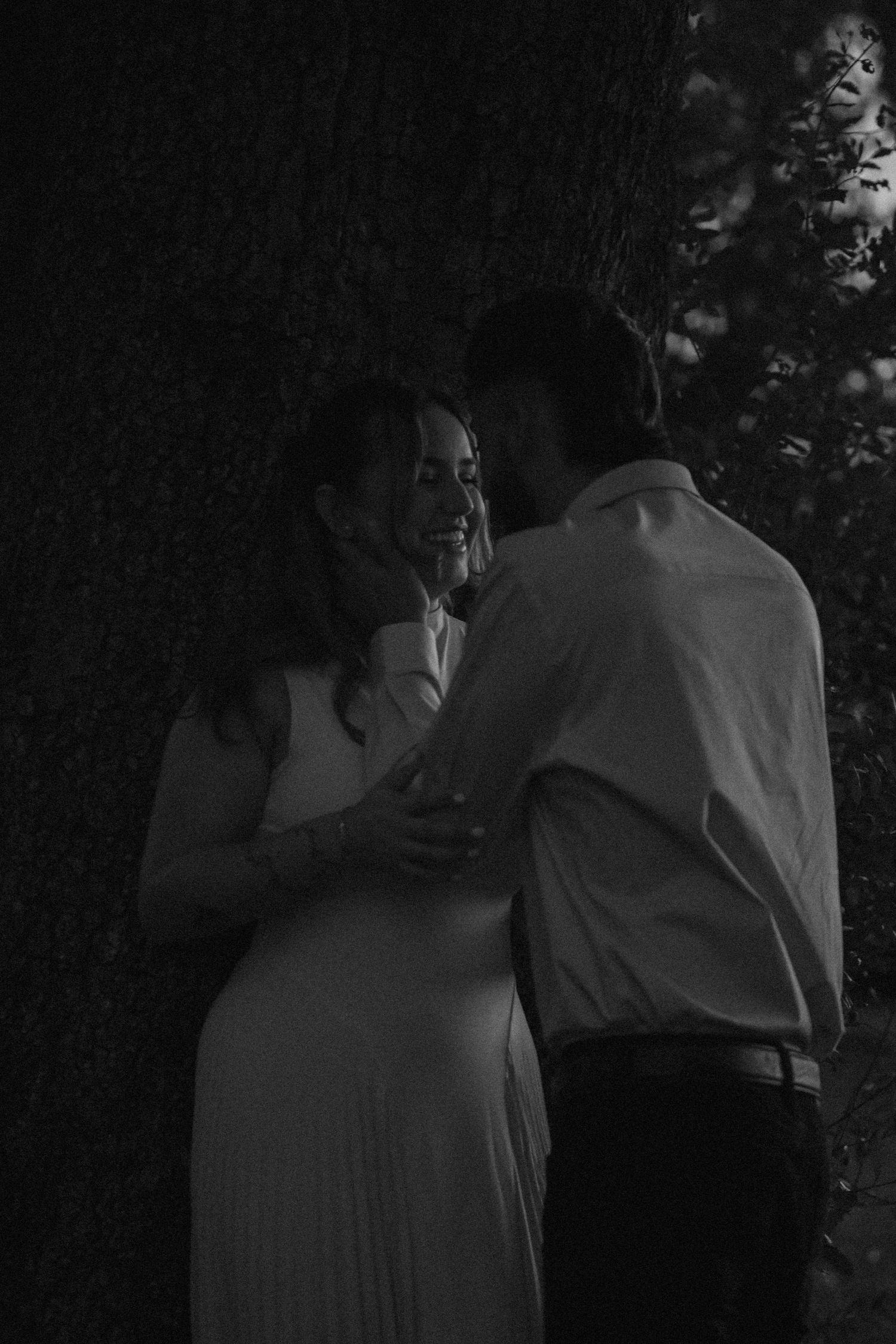 A couple shares an intimate moment in a darkened outdoor setting.