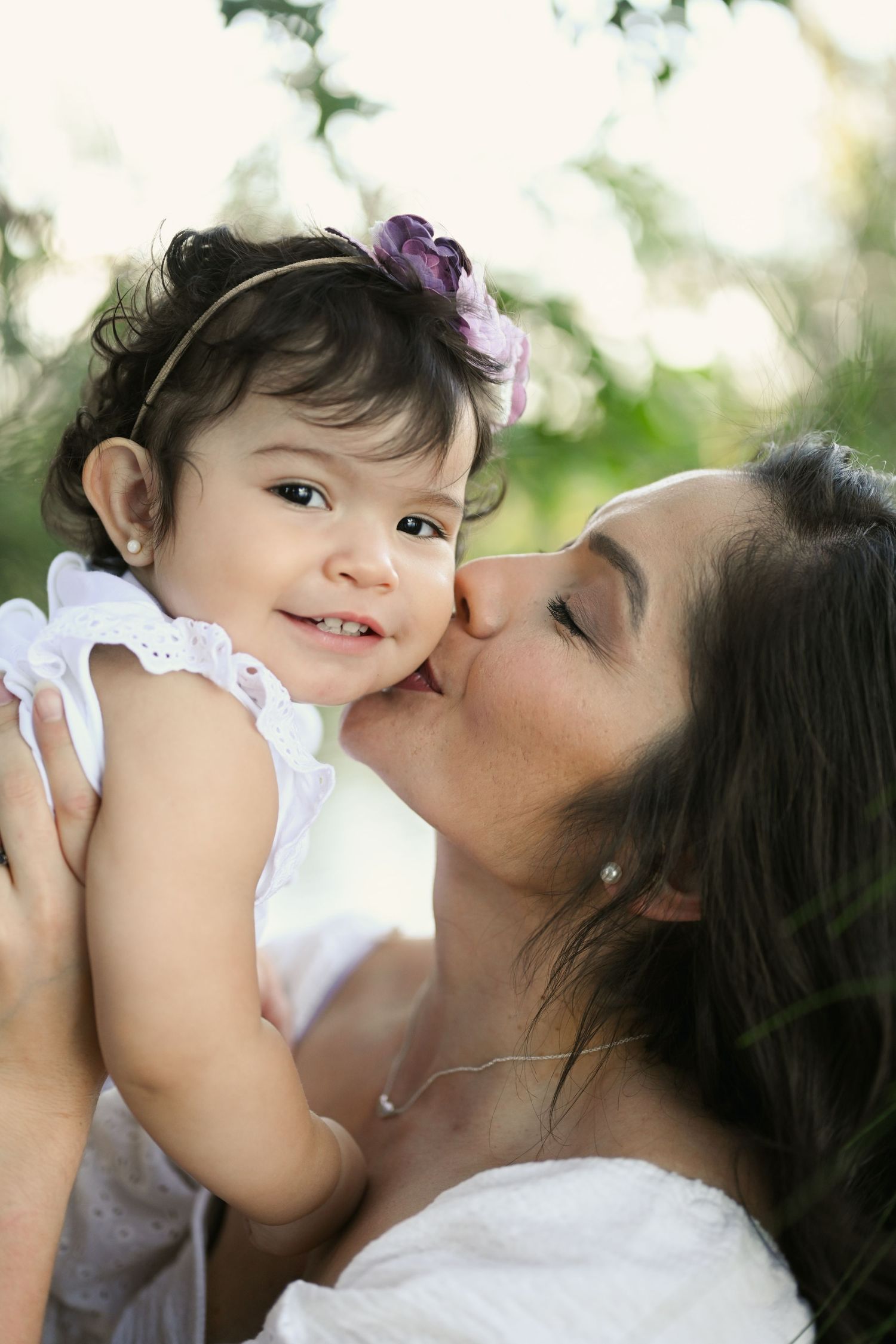 Tender moments between parent and child with matching white outfits in nature.