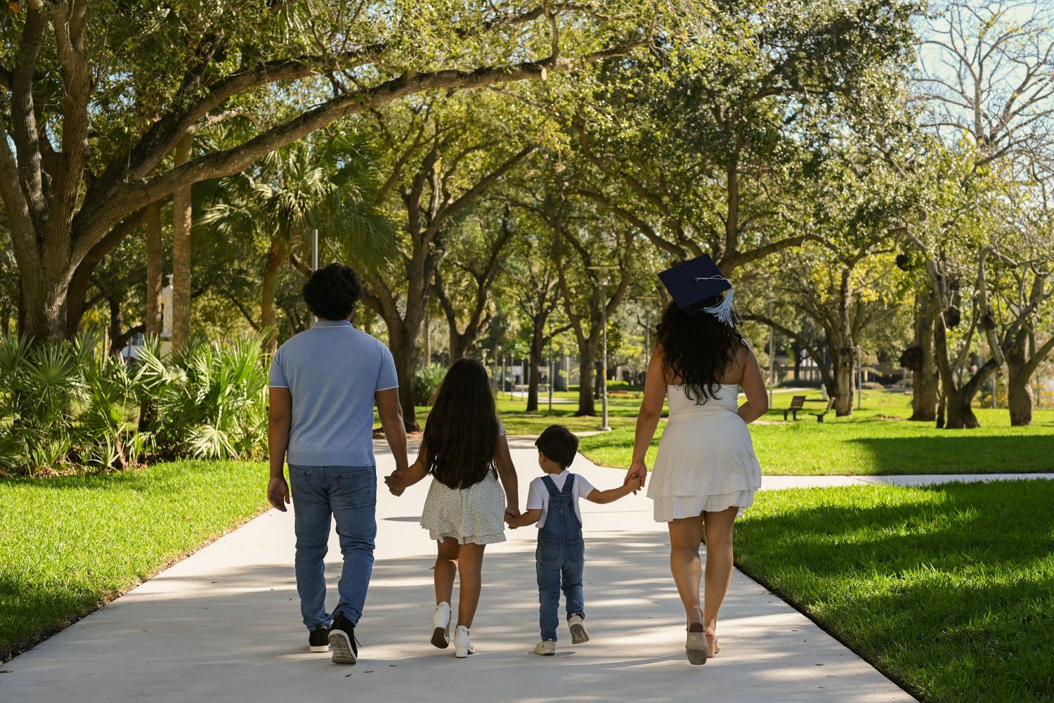 People walking together on a scenic garden path surrounded by trees.