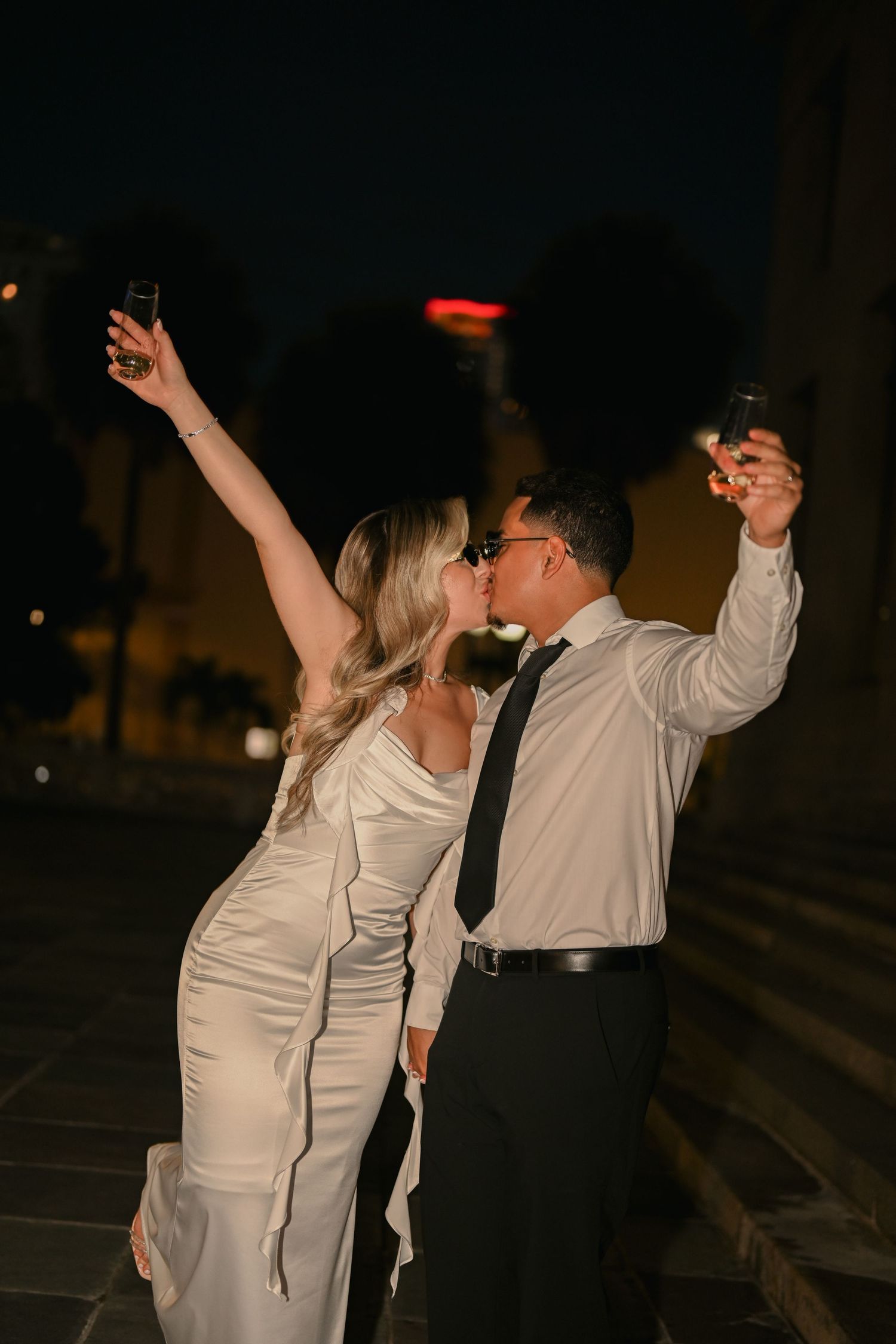 A couple in formal wear dances energetically at night on stone steps.