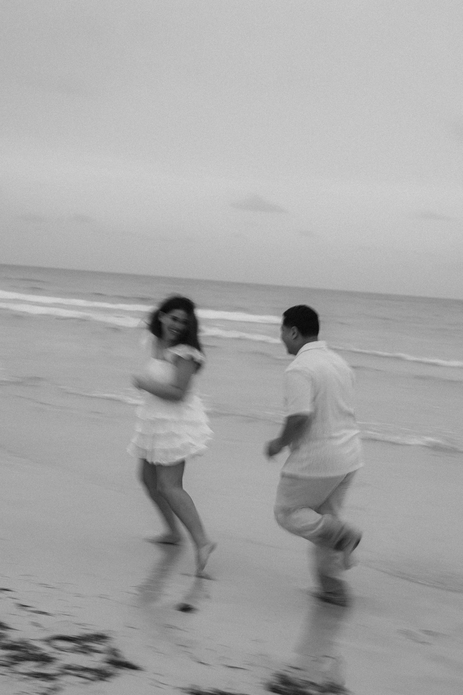 Motion-blurred photos of a couple playfully running on the beach.