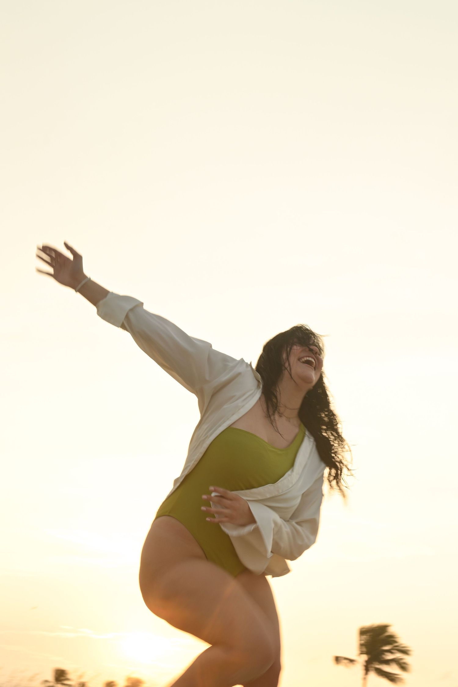 Expressive dance poses against a golden sunset sky near the ocean.