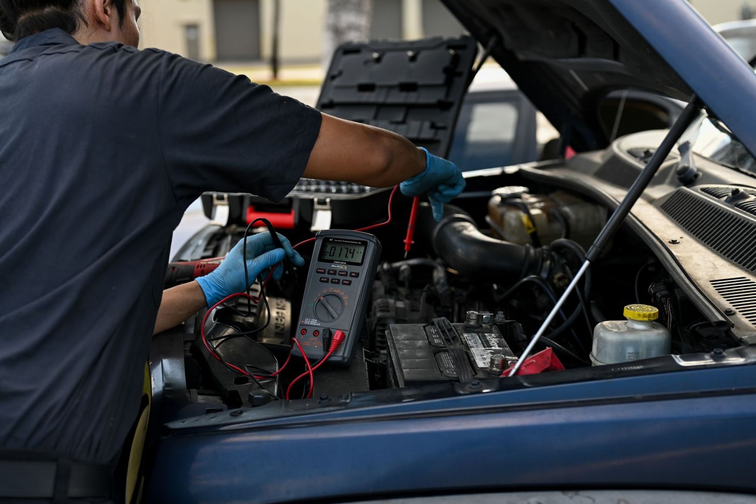 Technician leaning over engine bay while performing vehicle maintenance.