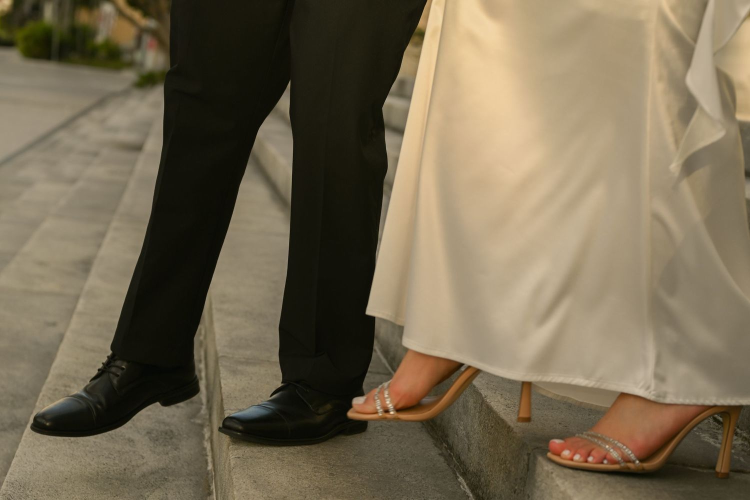Close-up detail shot of formal wedding attire and footwear on stone steps.