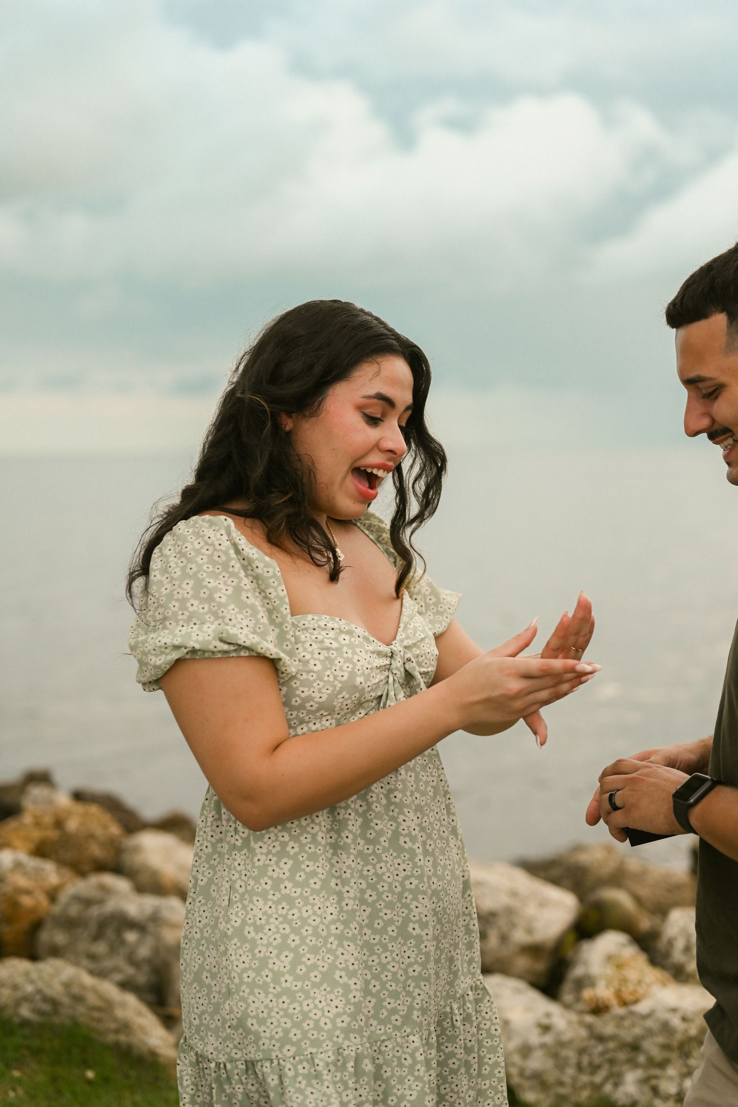 A joyful reaction captured during a romantic seaside proposal moment.