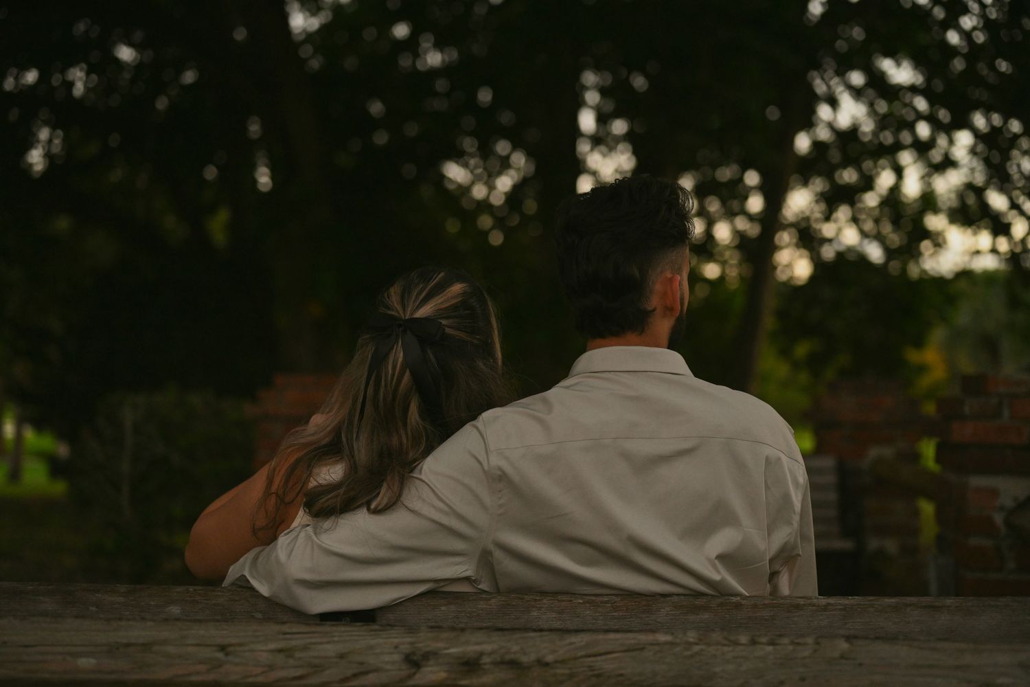 Romantic couple resting on wooden steps surrounded by greenery.