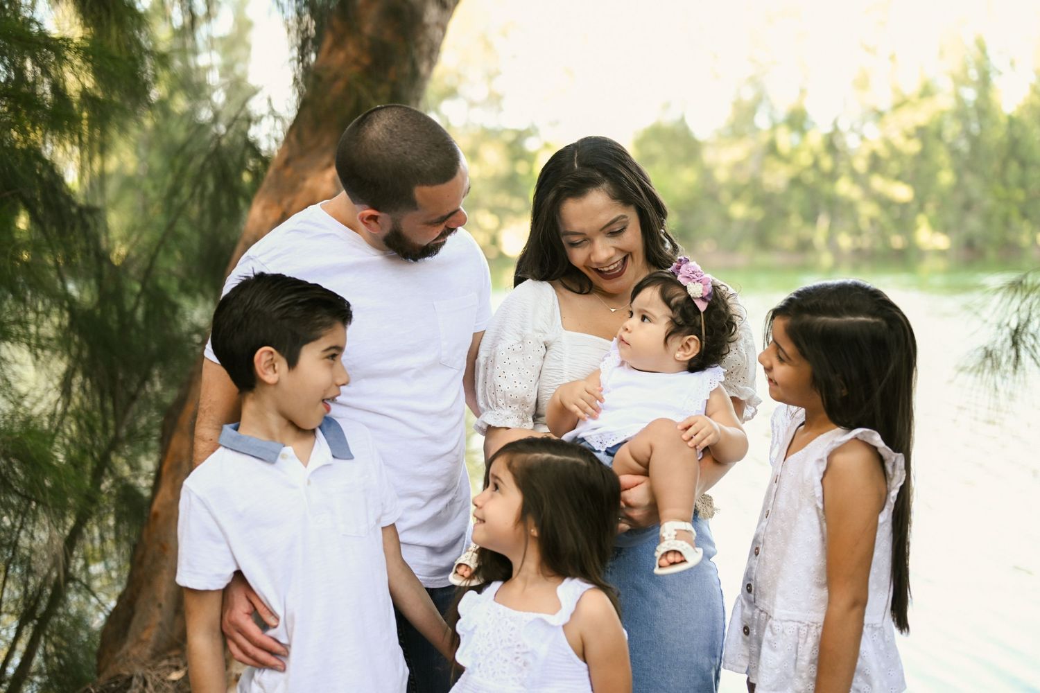 Family enjoying playful moments together outdoors near a lake.