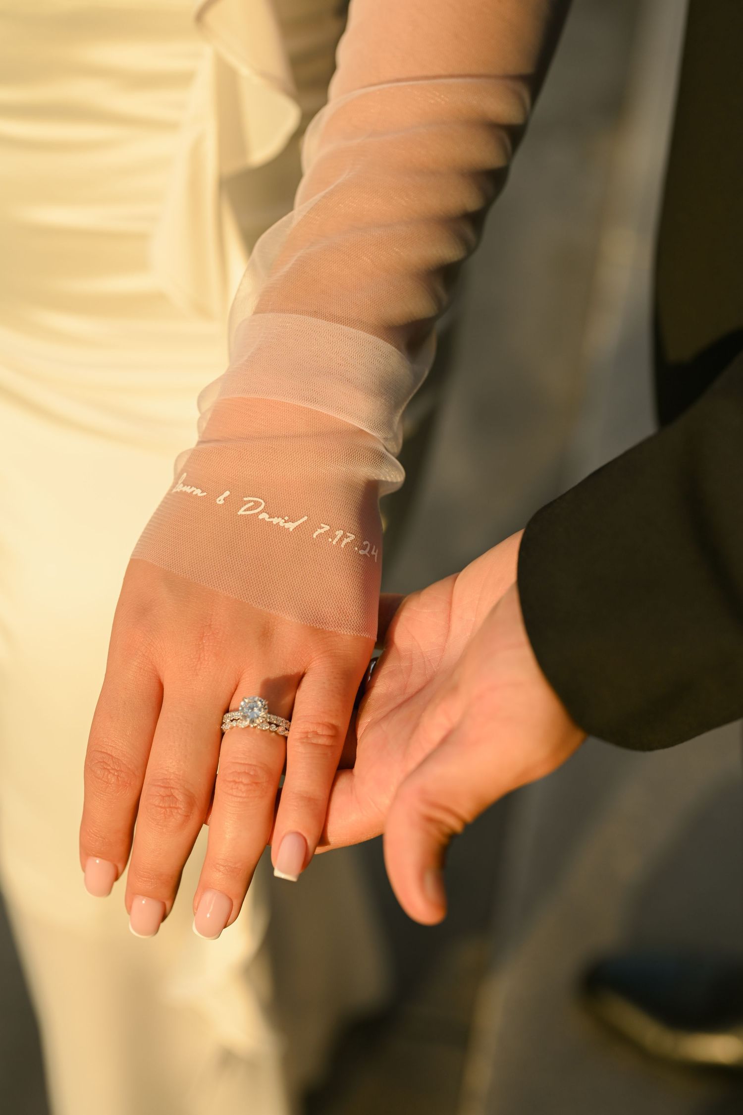 Close-up shot of hands wearing white long sleeves showing an engagement ring on a finger.