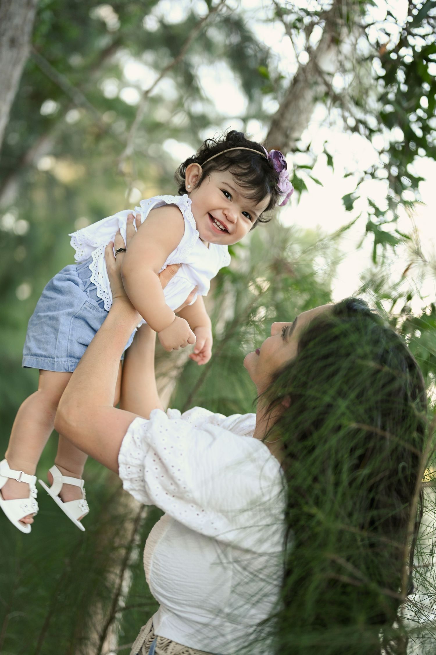 Joyful playtime between parent and child lifting up in the air among trees.