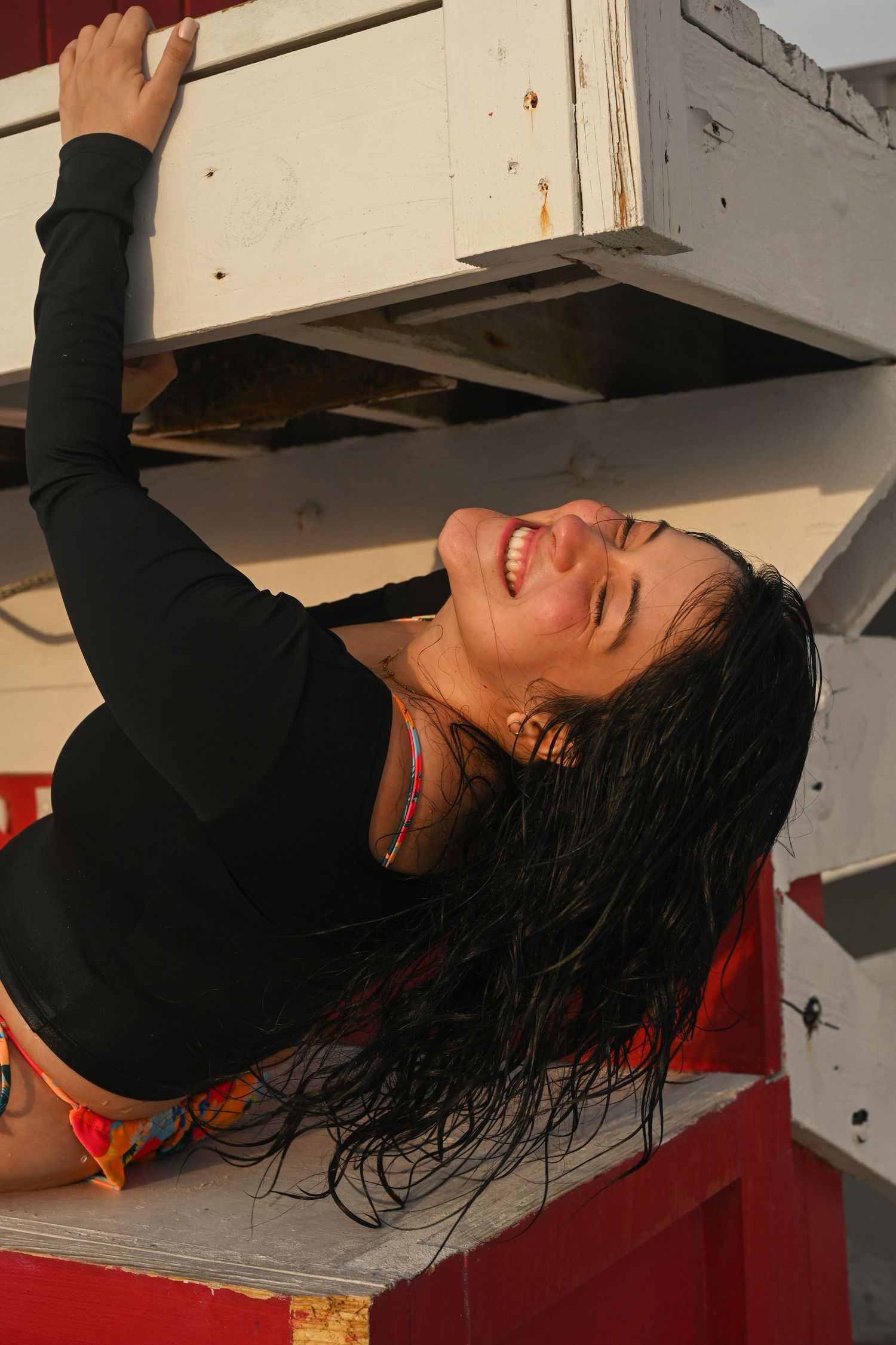 Figure with wet hair lying back on wooden platform.