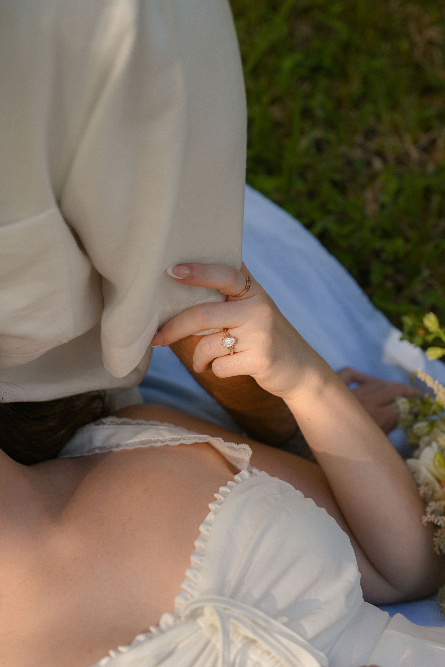 Close-up detail of delicate white lace fabric and jewelry in natural outdoor lighting.