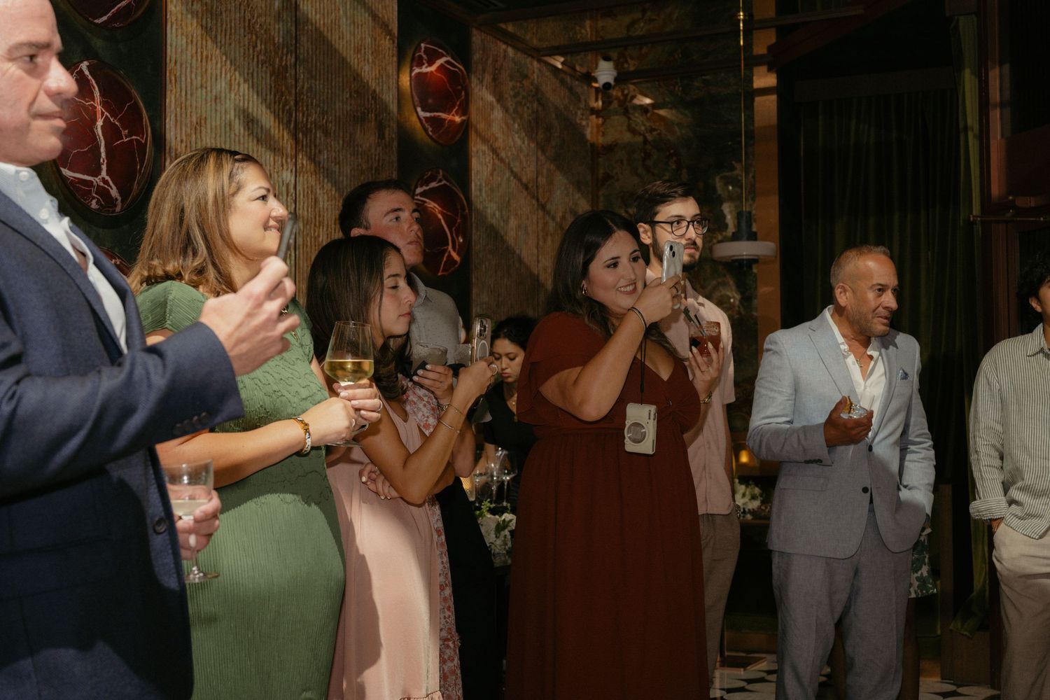 Guests raising glasses in a toast at an elegant indoor engagement party celebration.