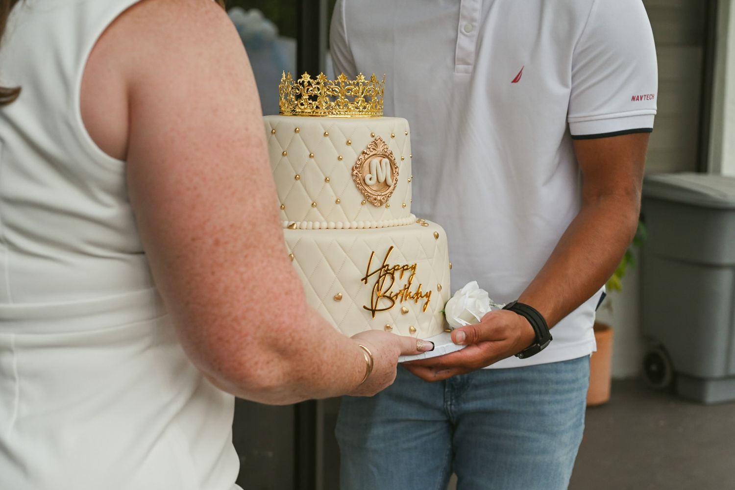 Elegant white tiered wedding cake with gold crown topper displayed at reception.