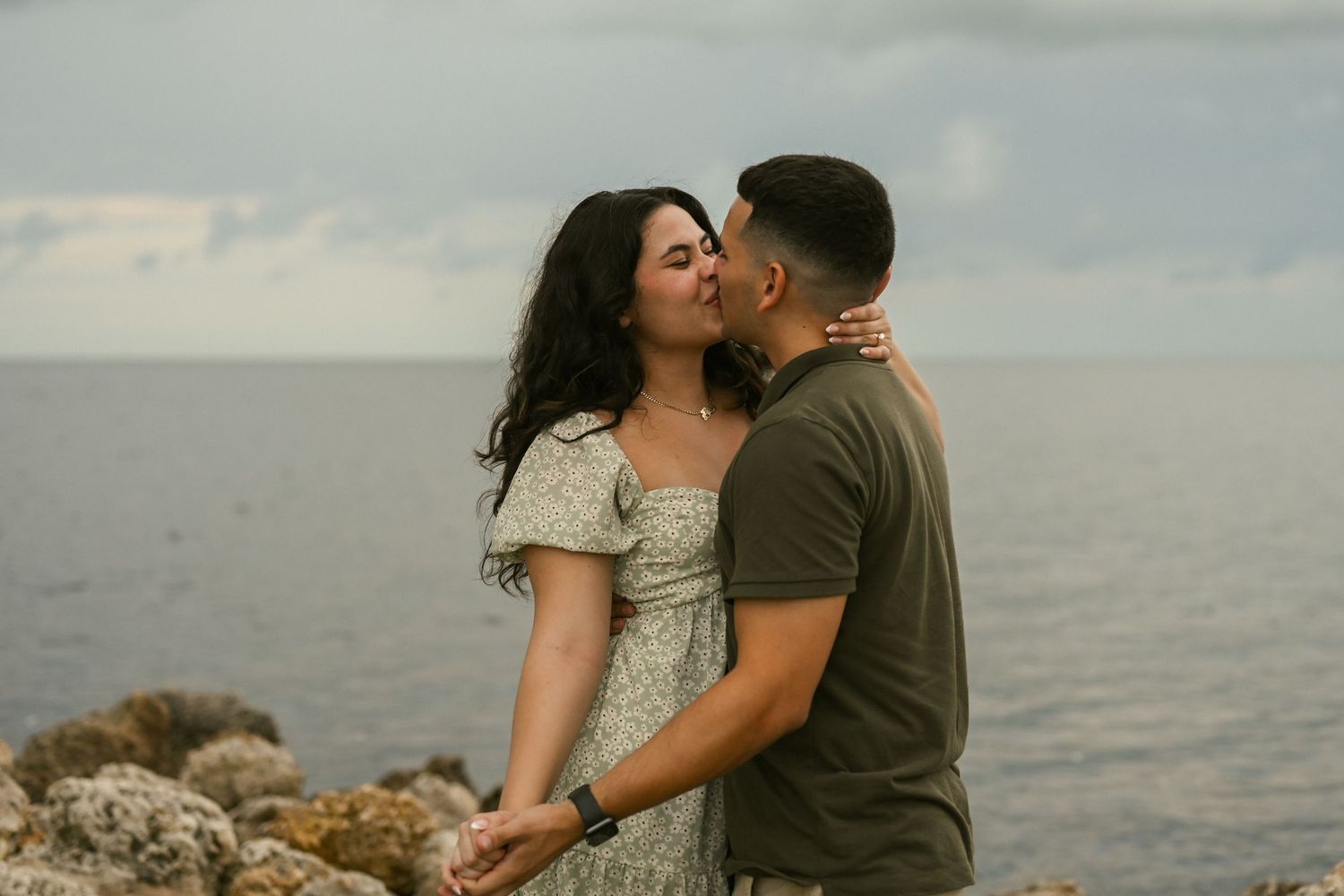 A couple shares romantic moments during their coastal engagement session.