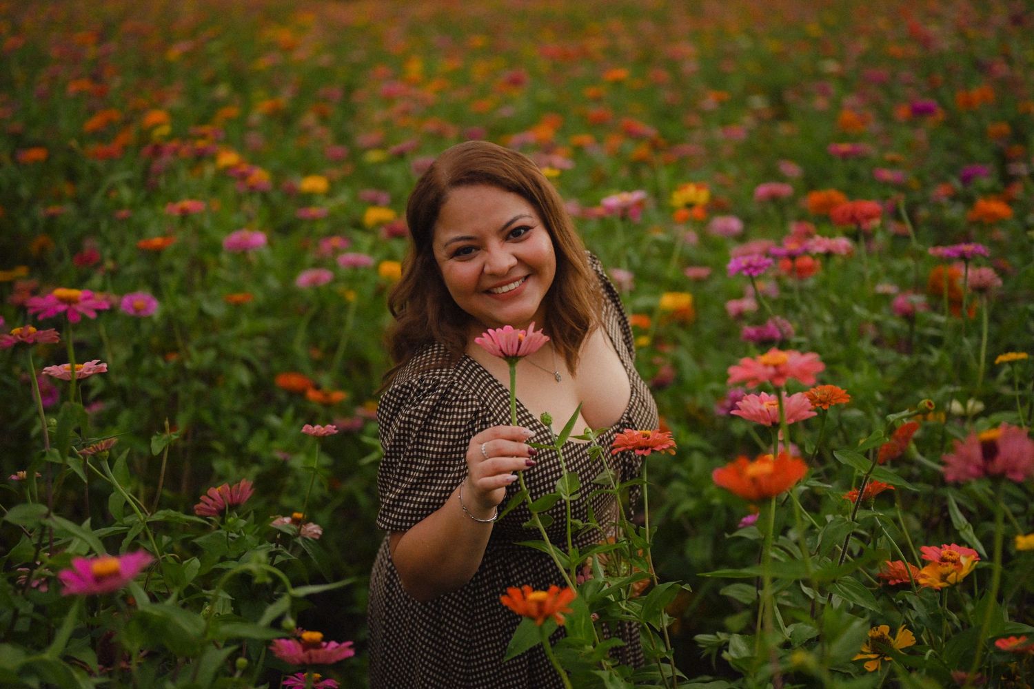 A vibrant flower garden filled with pink and orange zinnias blooms in lush greenery during summer.