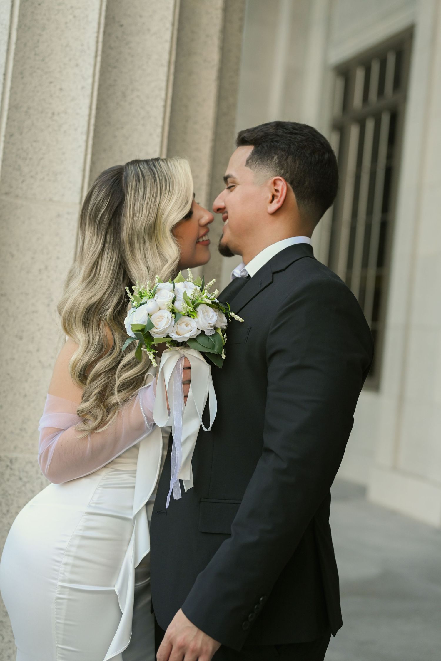 Wedding couple sharing romantic moment in front of classical architecture.