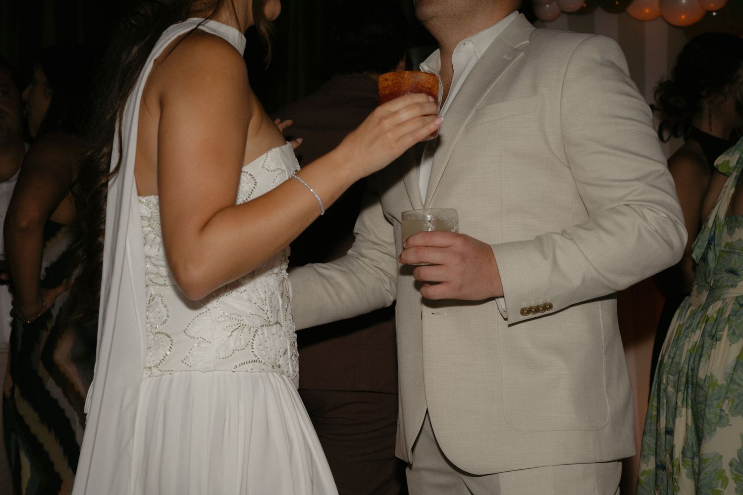 Bride in white wedding dress and groom in beige suit sharing a dance at an elegant wedding reception.