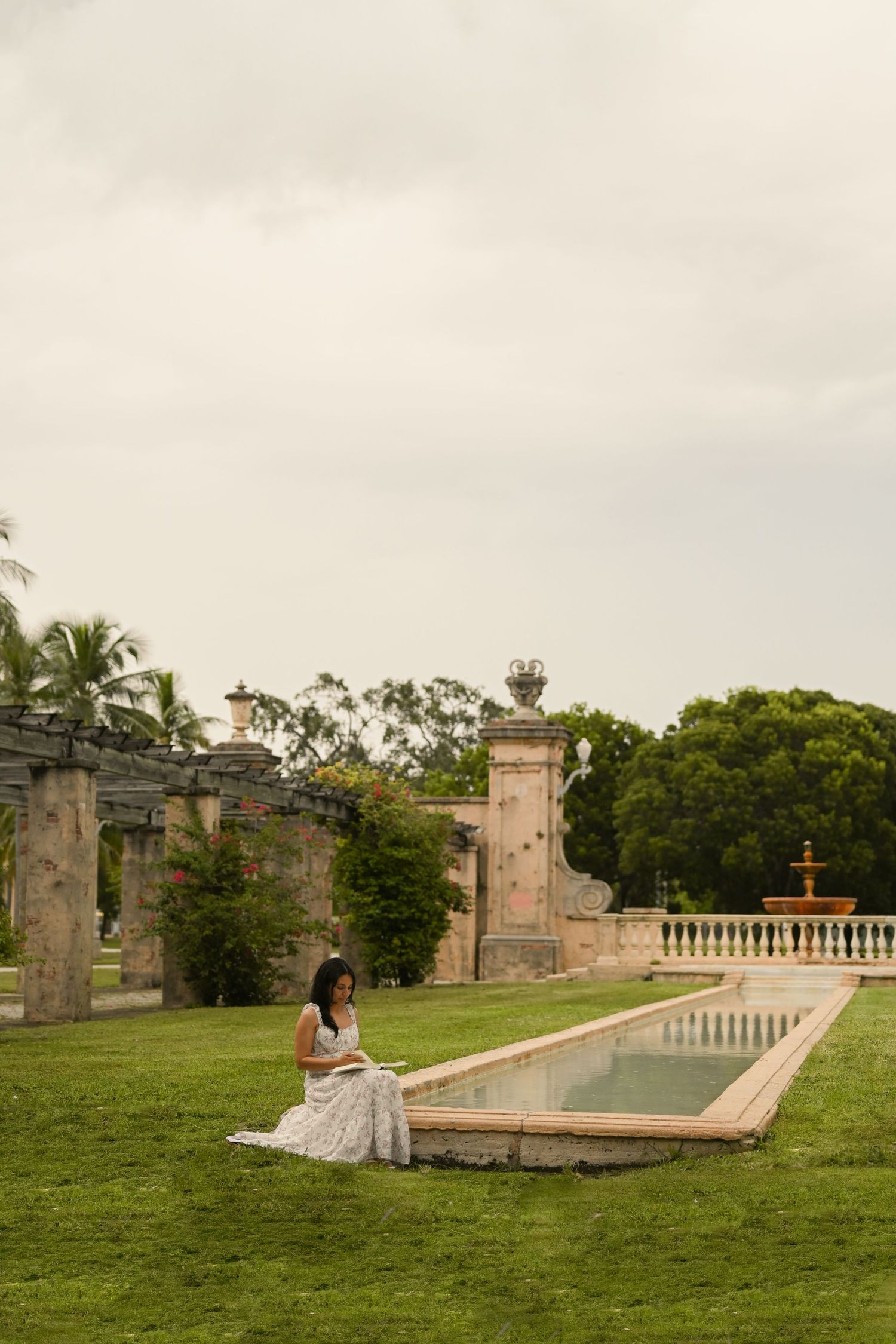 A scenic garden view with stone architecture and a long reflecting pool surrounded by green lawns.