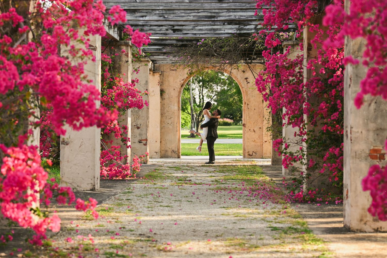 Beautiful pink bougainvillea flowers frame a stone archway walkway.