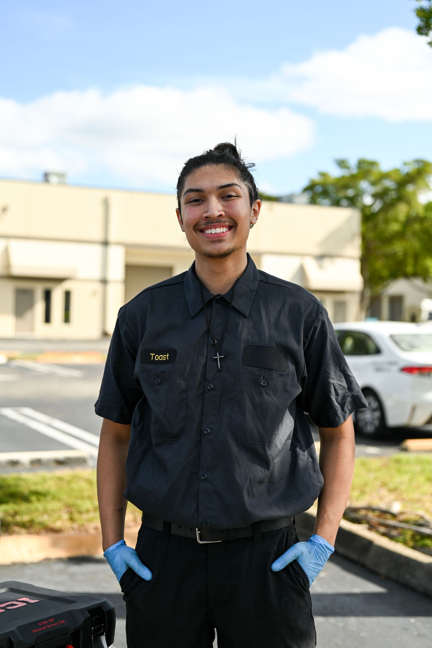 Security officer in black uniform posing confidently in a parking area.