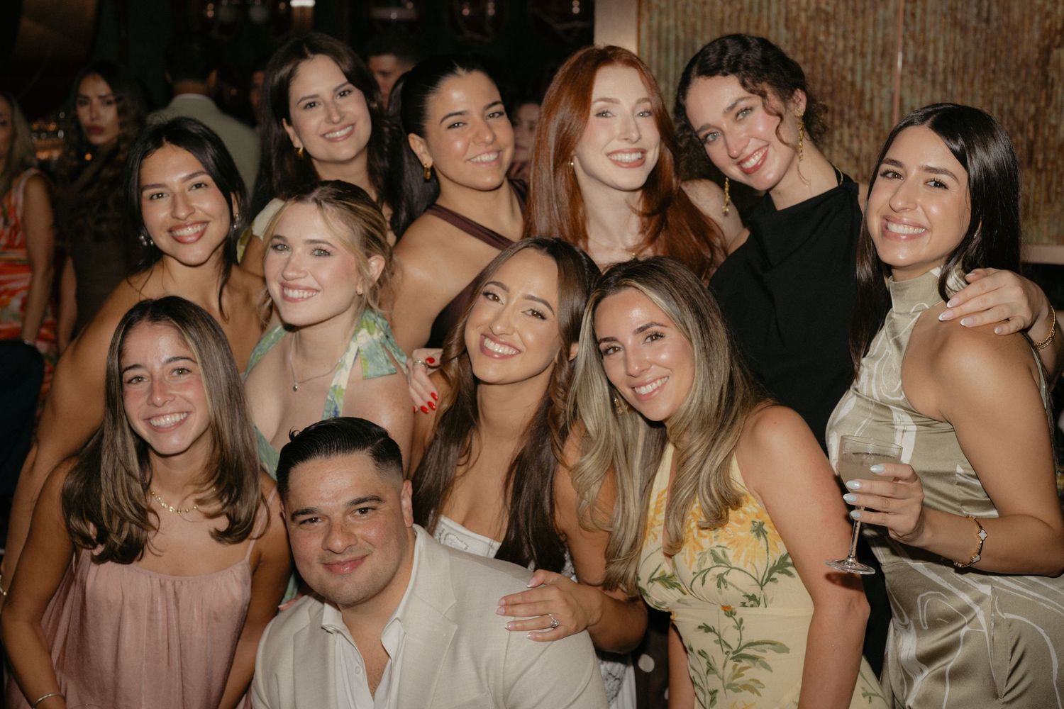 Group of smiling young adults posing together at a social gathering or party event indoors.