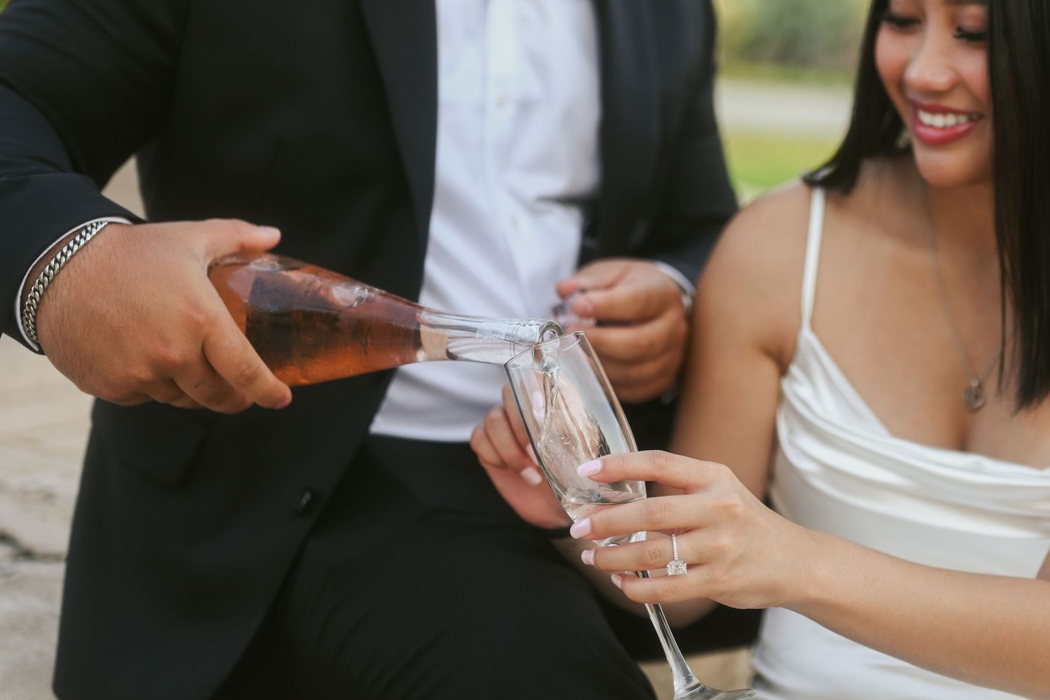 Hands holding champagne glasses during an outdoor celebration.
