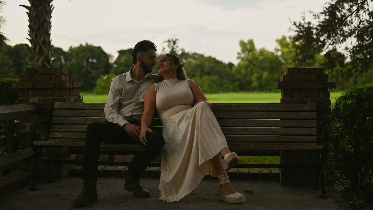 Couple sitting together on wooden steps in a park during sunset.
