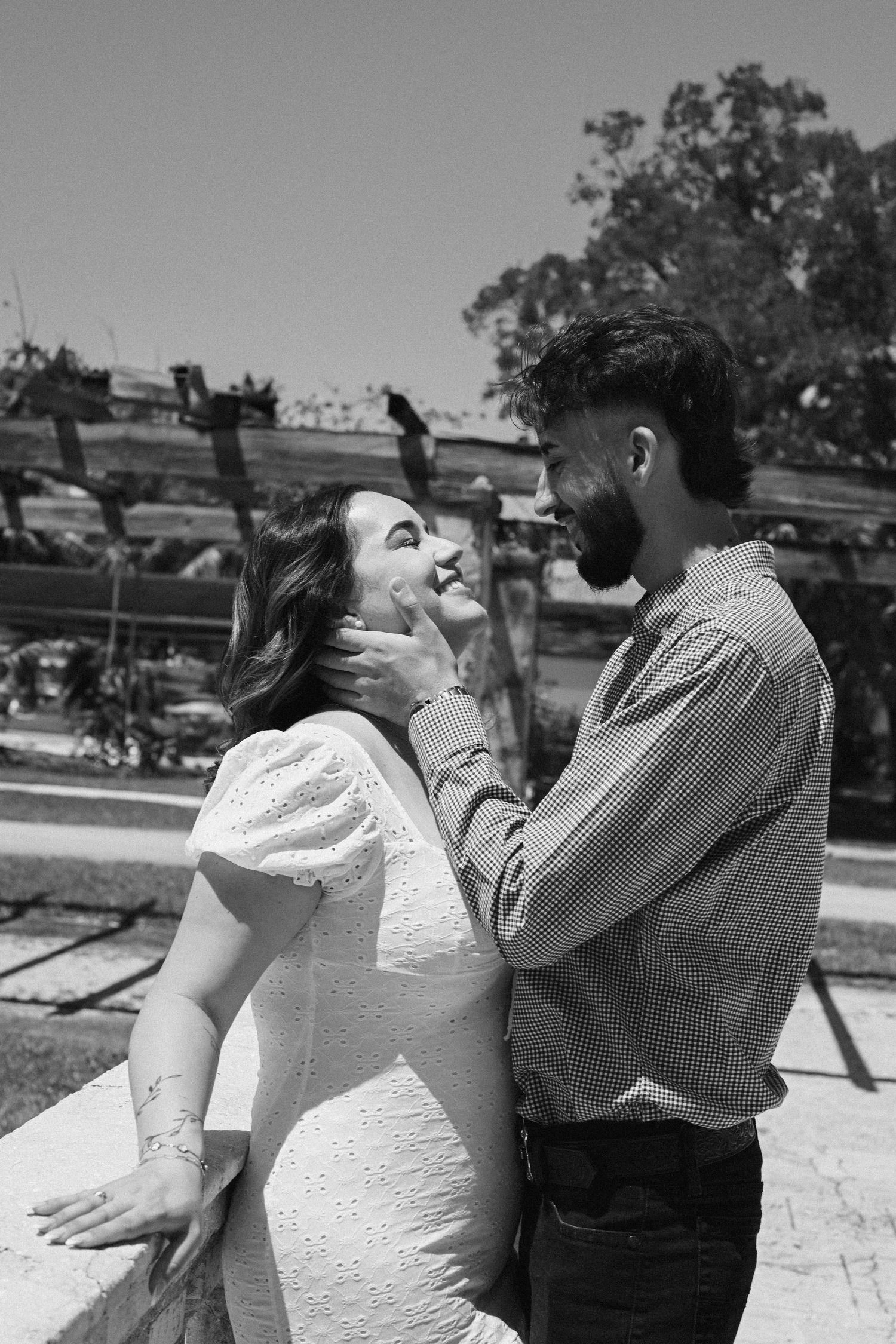A couple shares intimate moments in an outdoor setting with natural lighting.