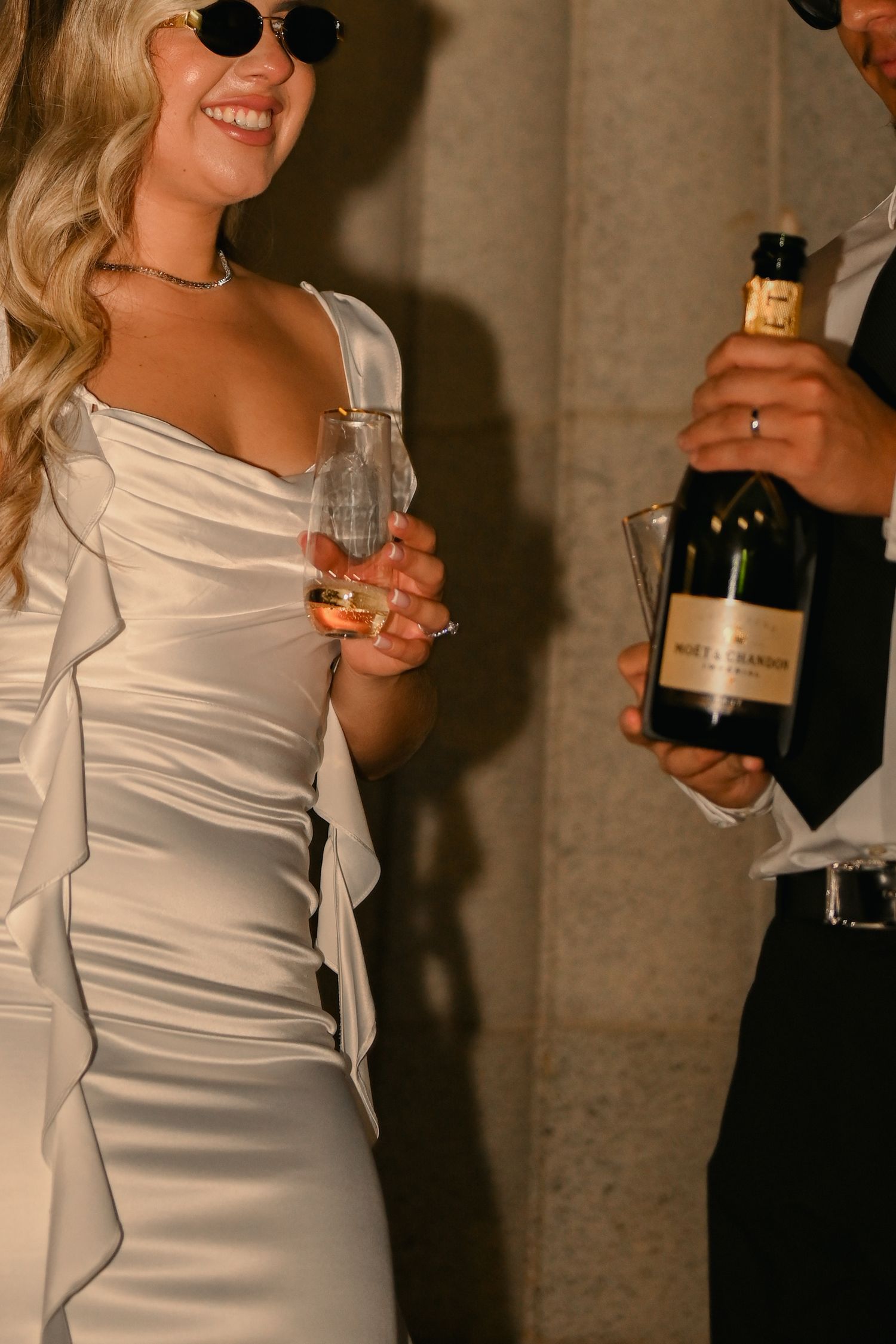 Wedding couple in formal attire sharing drinks and laughter.