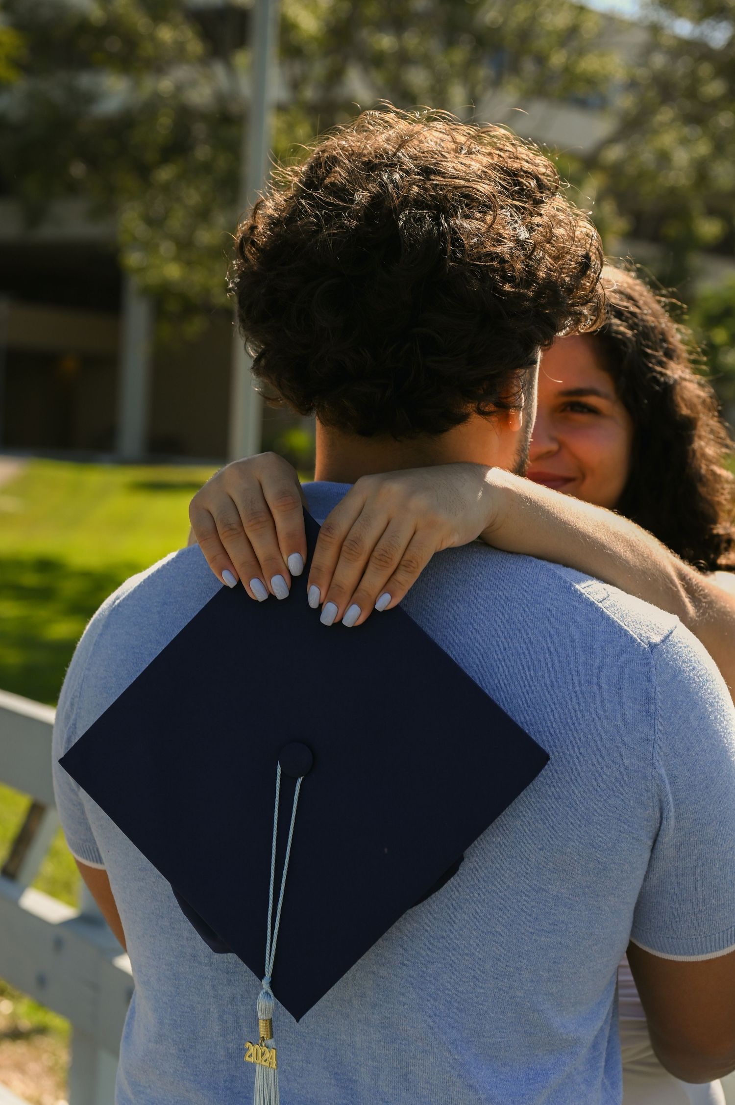 A couple sharing an intimate embrace outdoors on a sunny day.