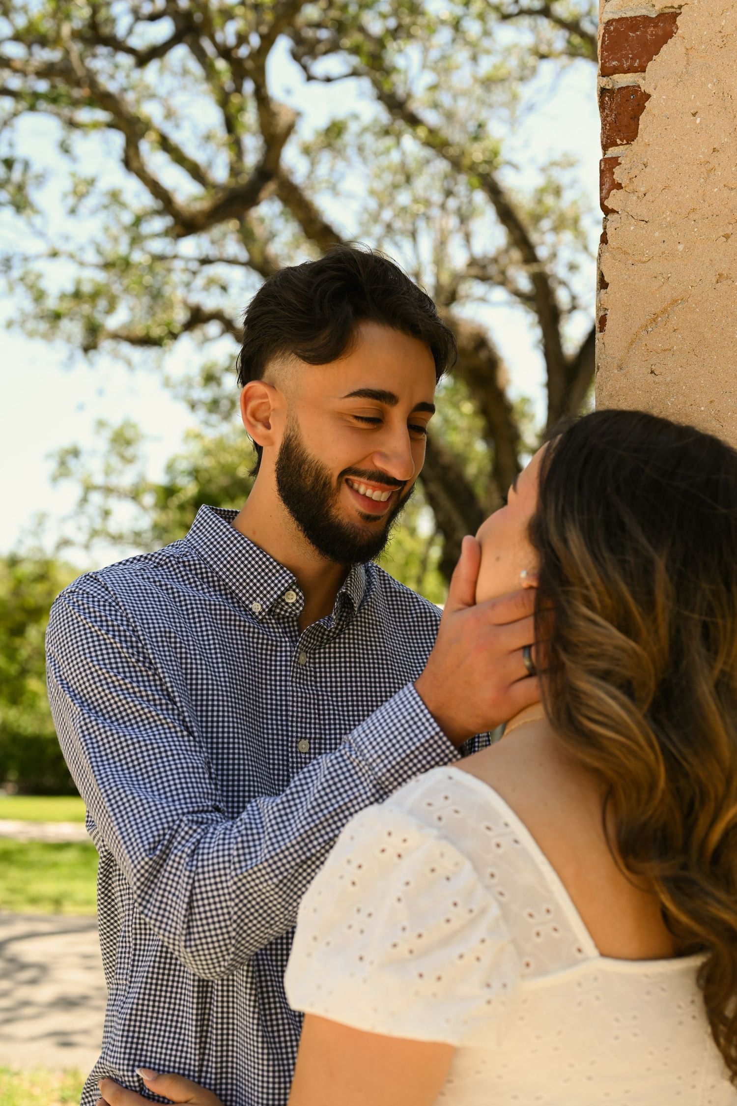 Couple sharing intimate moment against rustic stone column backdrop.