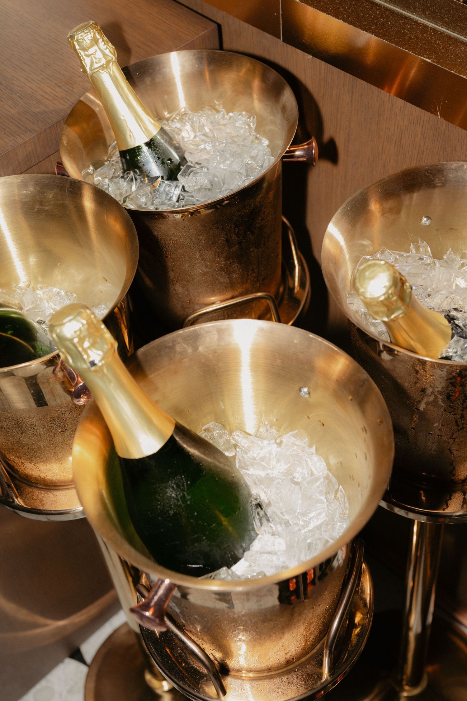 Multiple gold champagne buckets filled with ice and champagne bottles for a wedding.