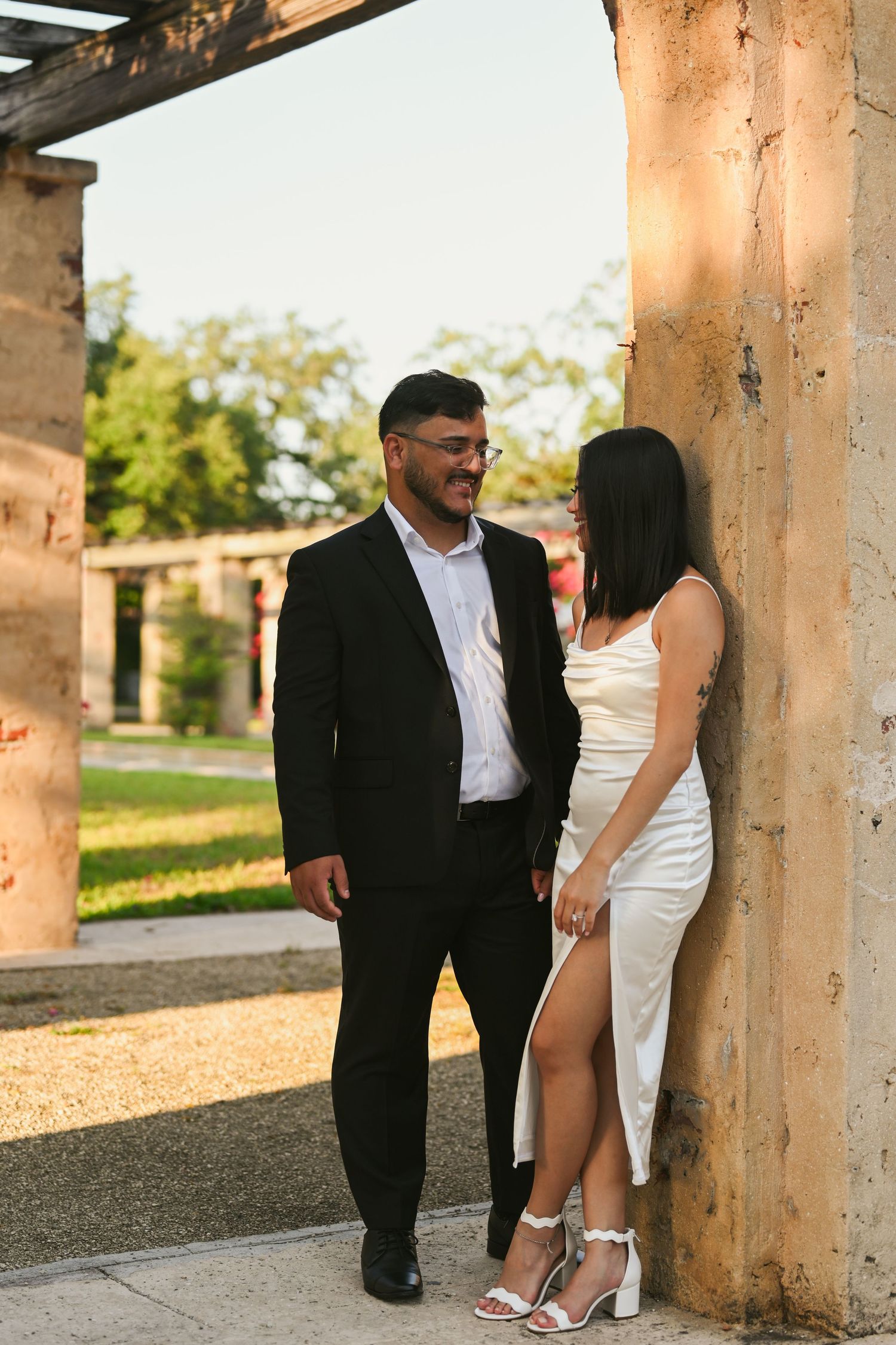 Couple posing between stone columns in an elegant outdoor setting.