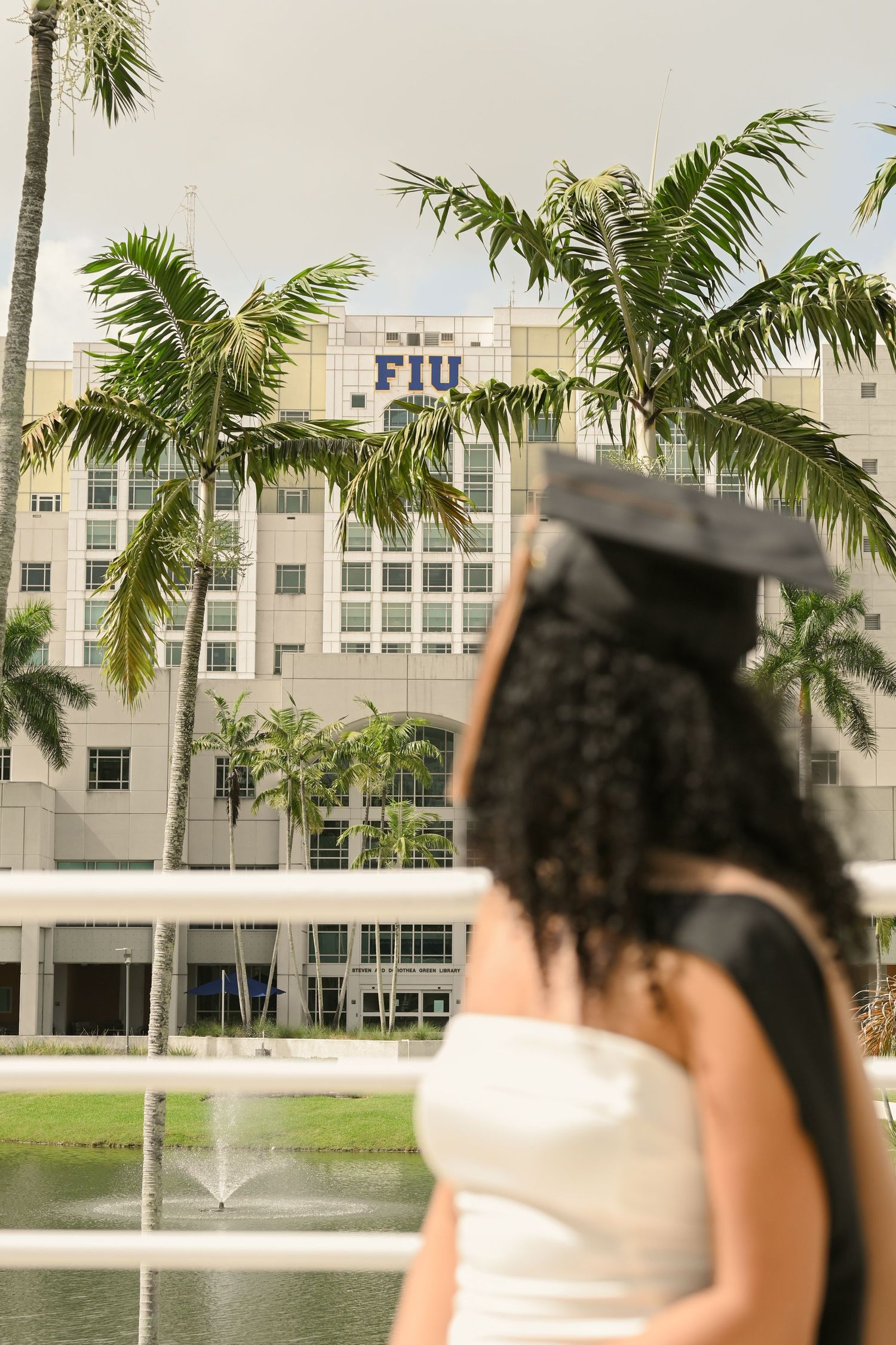 FIU campus buildings and palm trees serve as backdrop for graduation photos.