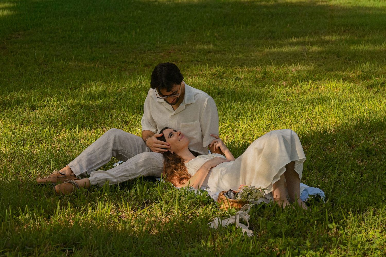 A person relaxes on a grassy lawn while reading a book on a sunny afternoon.