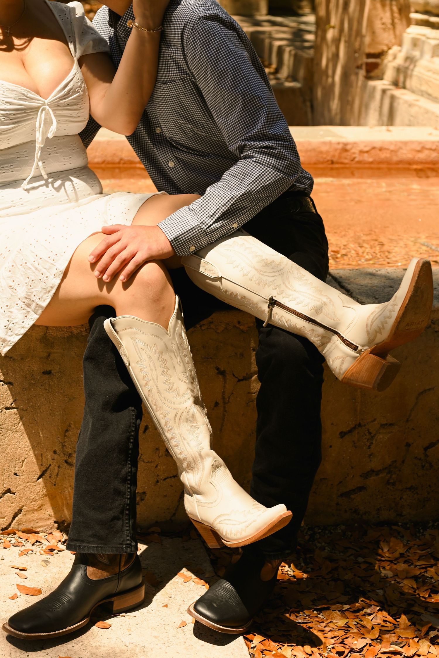 Close-up of contrasting footwear showing white boots and dark shoes on stone steps.