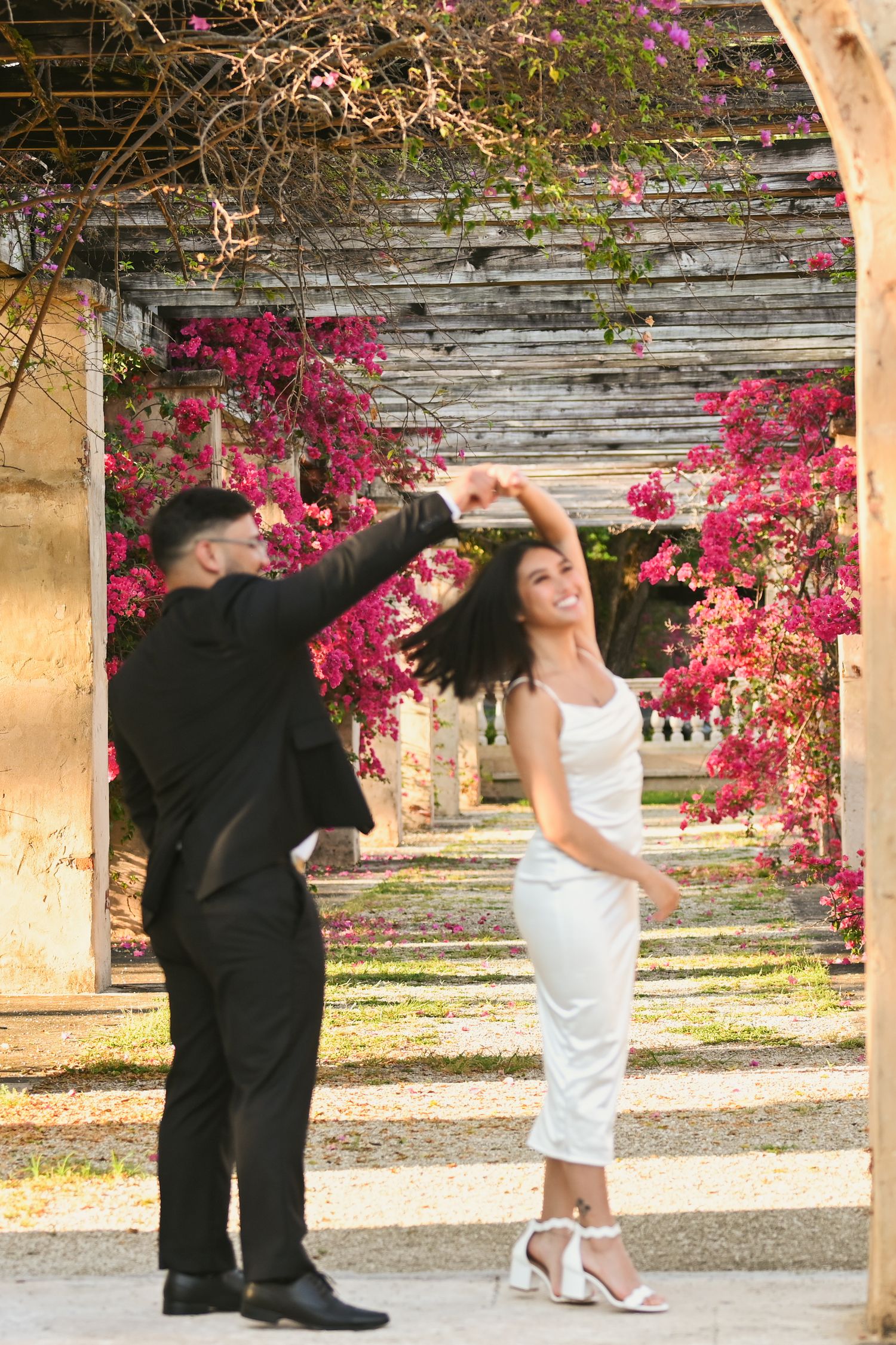 Playful dance moves under stone archways with flowering vines.