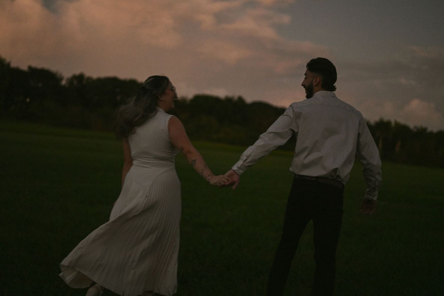 Couple dancing in open field during dramatic sunset.